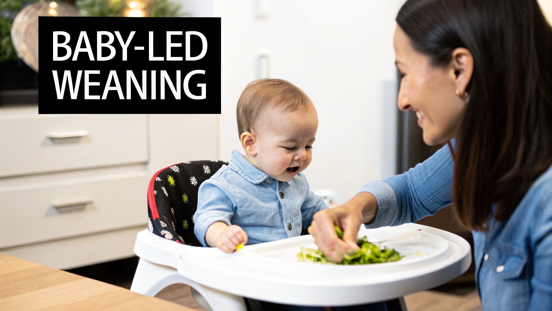 A happy baby in a high chair engaging in baby-led weaning with an adult, trying solid food.