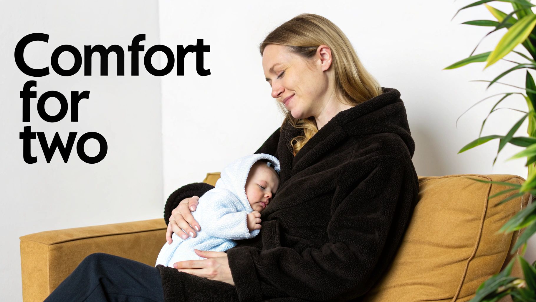 A smiling woman in a dark robe cradles a sleeping baby in a light blue hooded outfit, with text "Comfort for two."