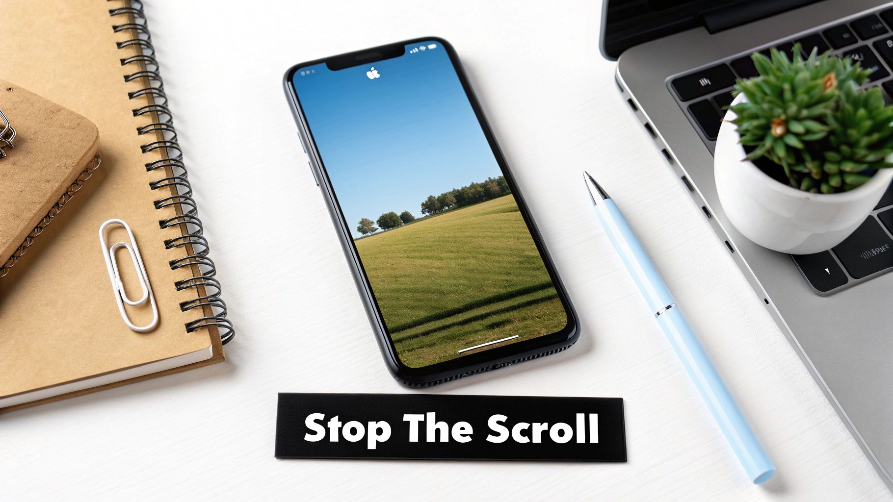 Phone on desk displaying landscape image with text below: “Stop The Scroll.”