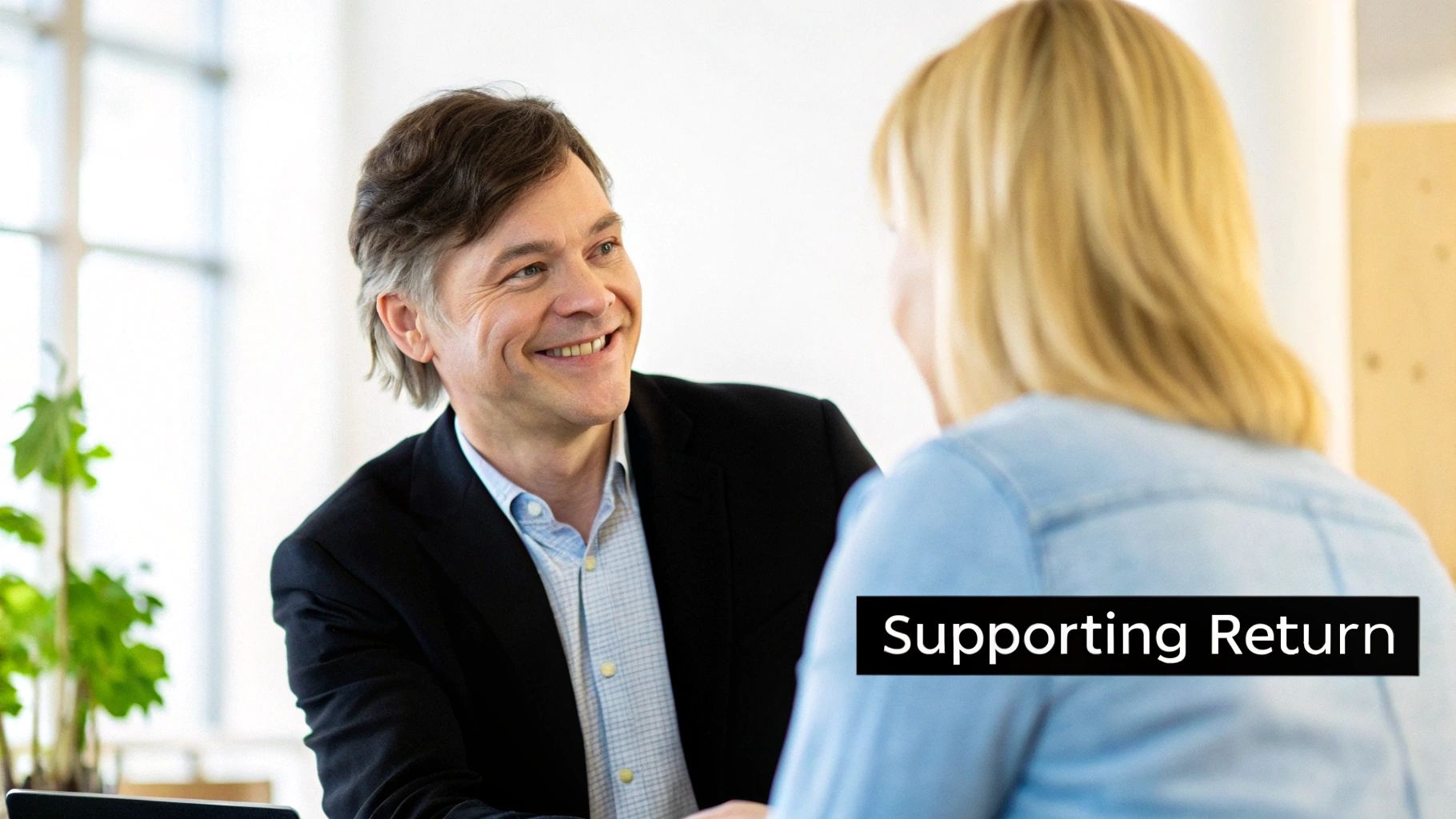 Two colleagues having a supportive conversation in a modern office setting.