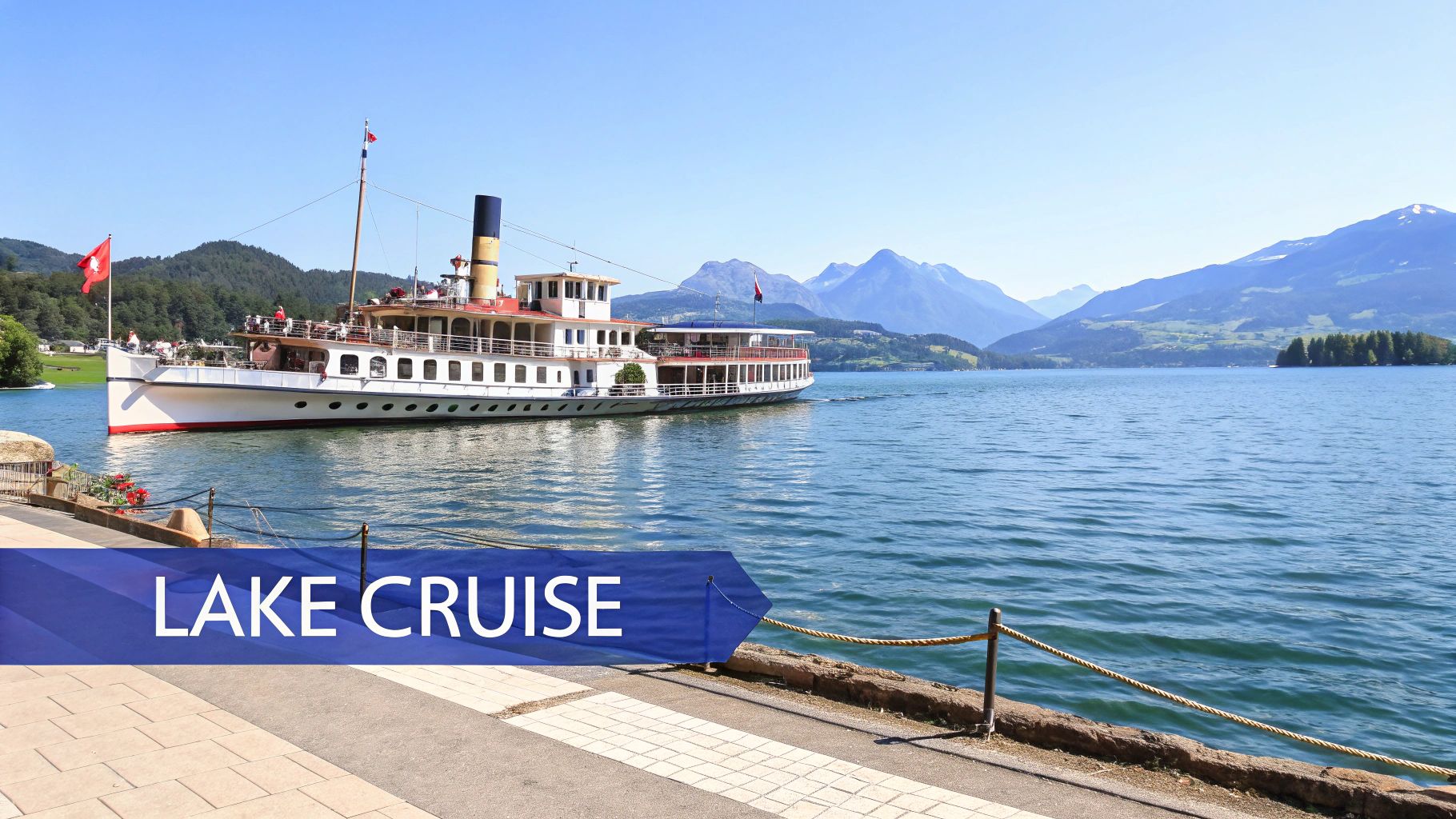 A scenic view of a classic paddle steamer sailing on a tranquil lake surrounded by mountains, with a 'LAKE CRUISE' banner.