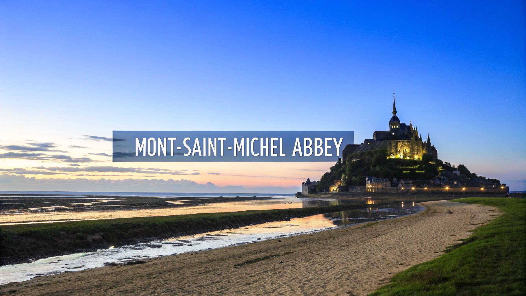Mont Saint Michel Abbey illuminated at sunset with tidal flats and sandy beach in Normandy France