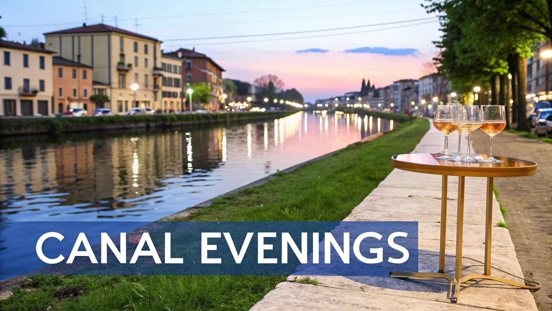 A charming canal scene at dusk with illuminated buildings, water reflections, and rose wine glasses on a table.