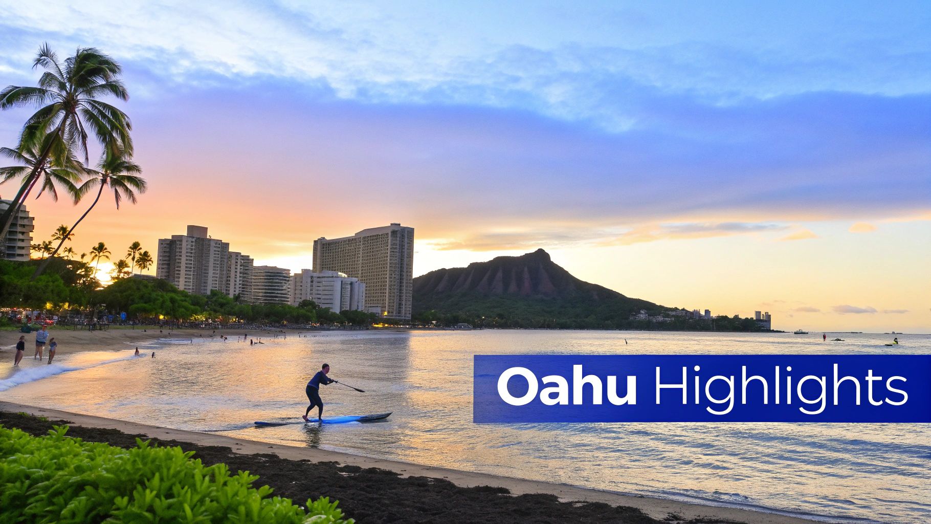 Beautiful sunset over Waikiki Beach, Oahu, with palm trees, buildings, and Diamond Head, as a person paddleboards.