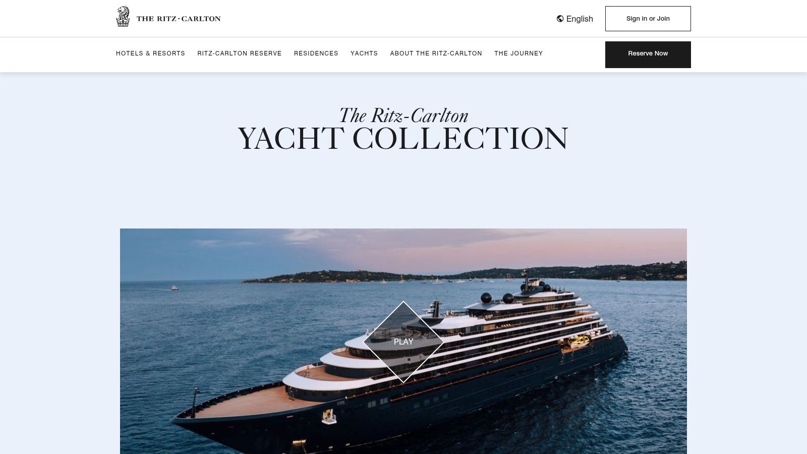 The Ritz-Carlton Yacht Collection sailing near a coastal town, showcasing its sleek, yacht-like design.