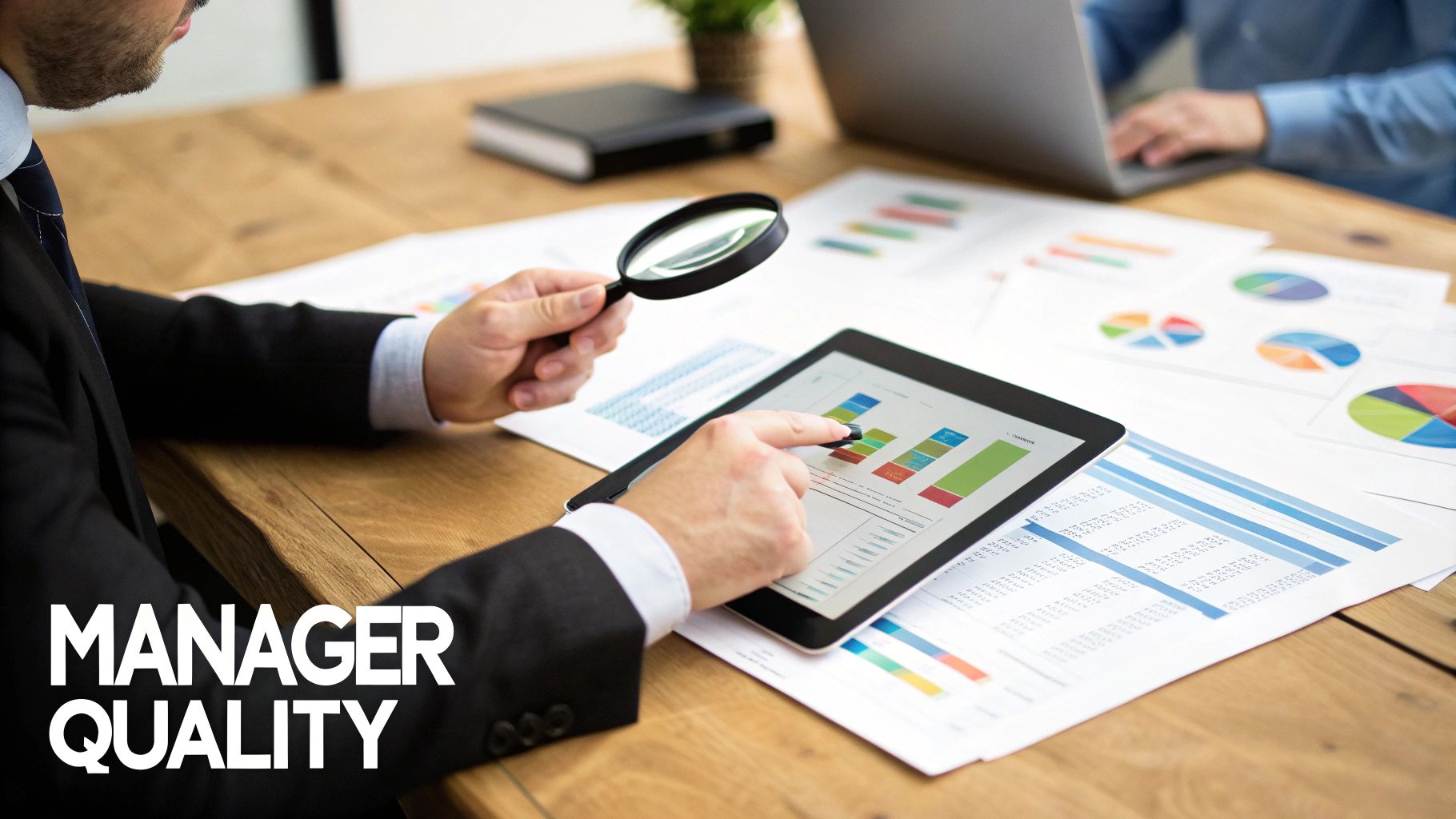 A person uses a magnifying glass and tablet to analyze financial data and charts on a desk.