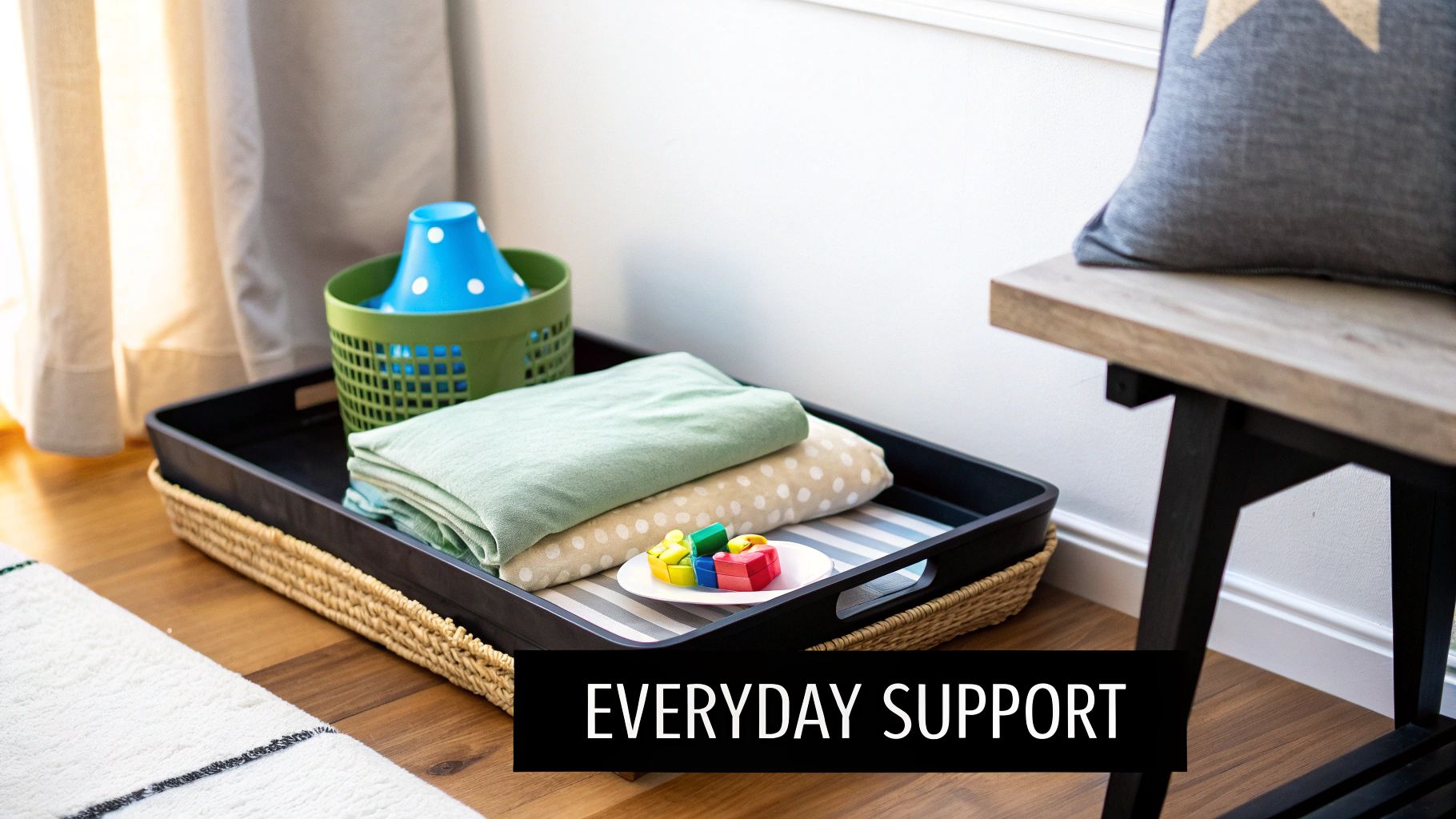 An organized basket and tray on a wooden floor holding blankets and bright sensory chew toys.