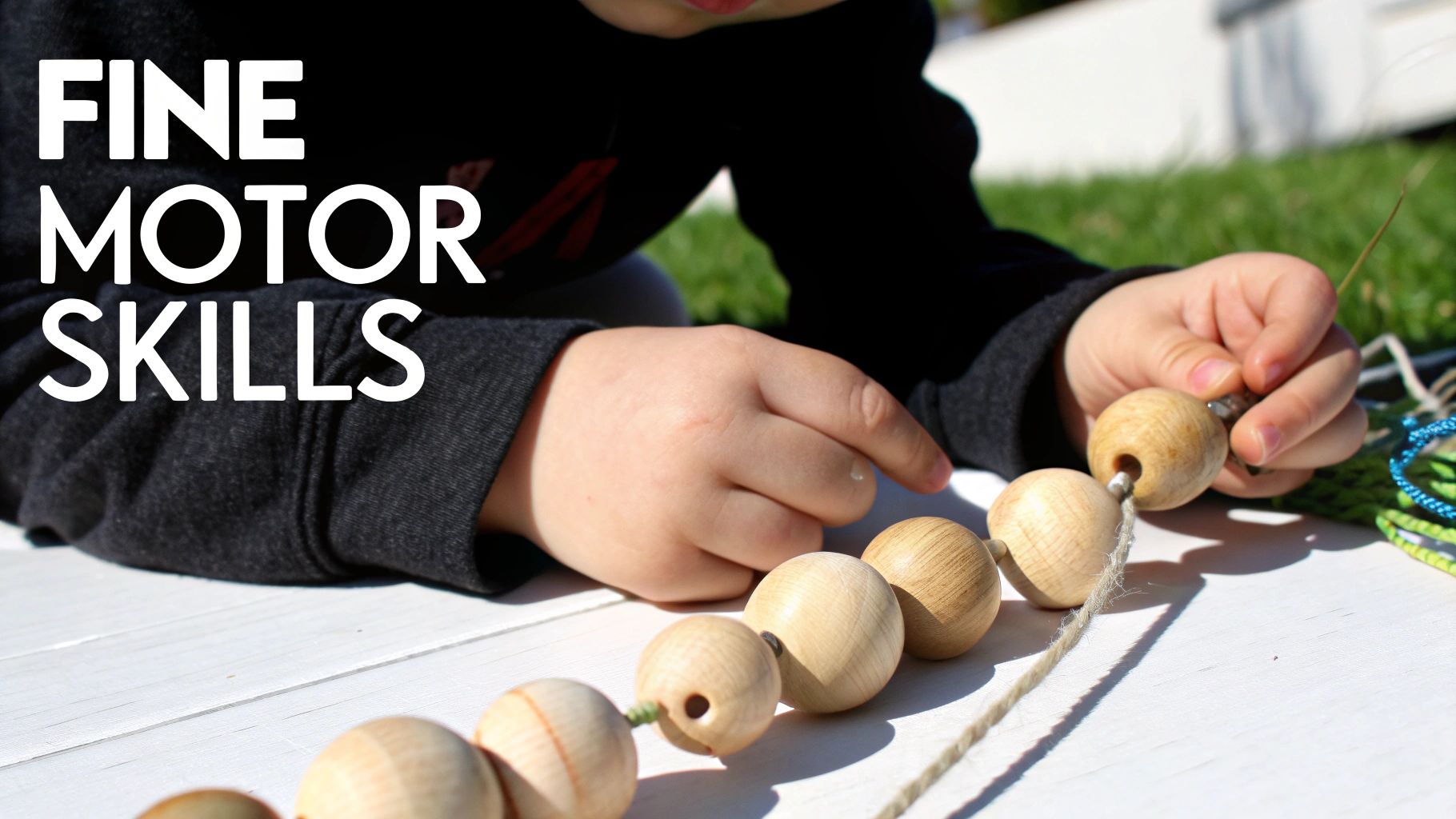 Close-up of a child's hands stringing wooden beads onto a string to develop fine motor skills.