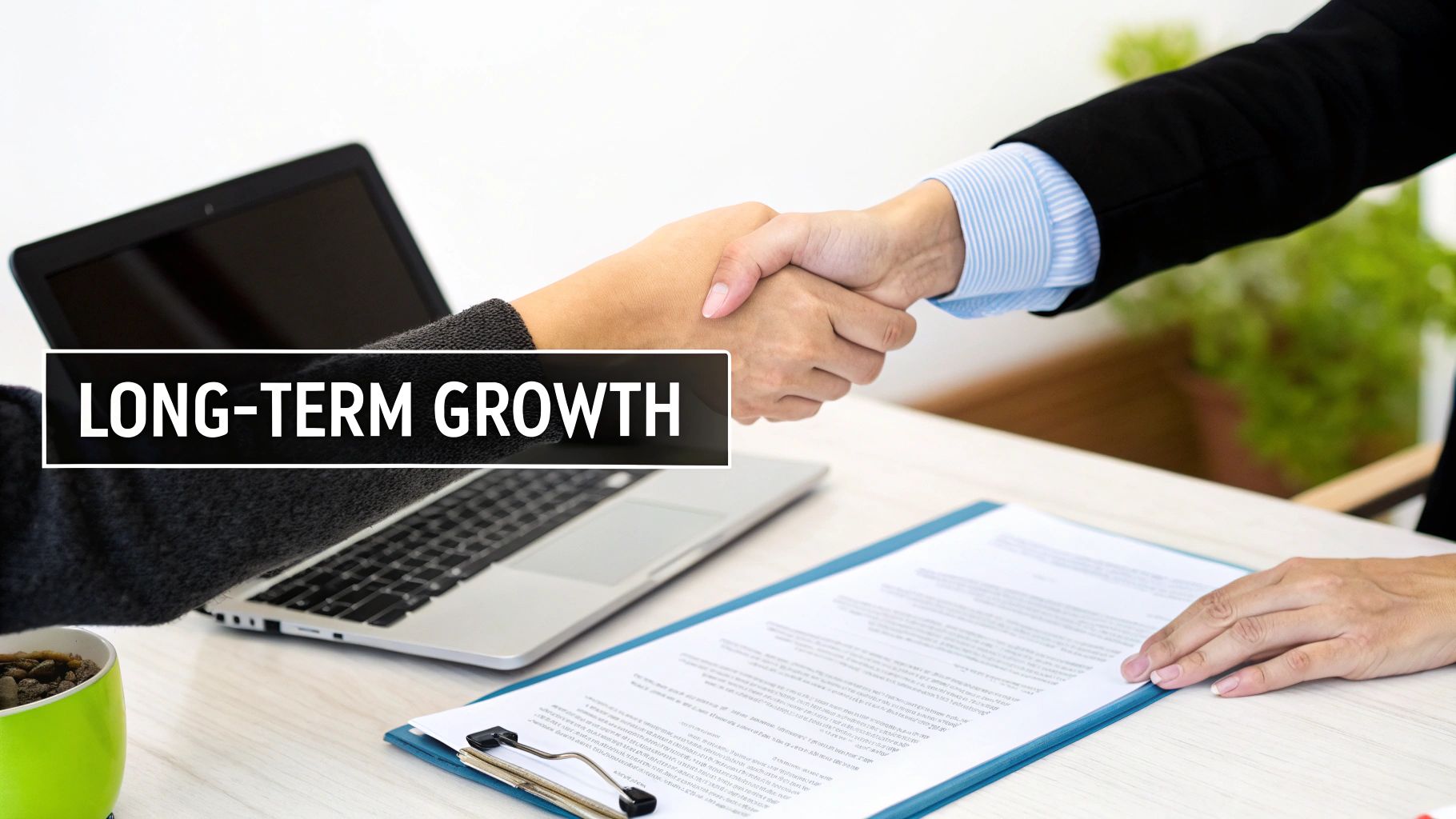 Two business people shaking hands over a desk with a laptop and document, featuring 'LONG-TERM GROWTH' text.