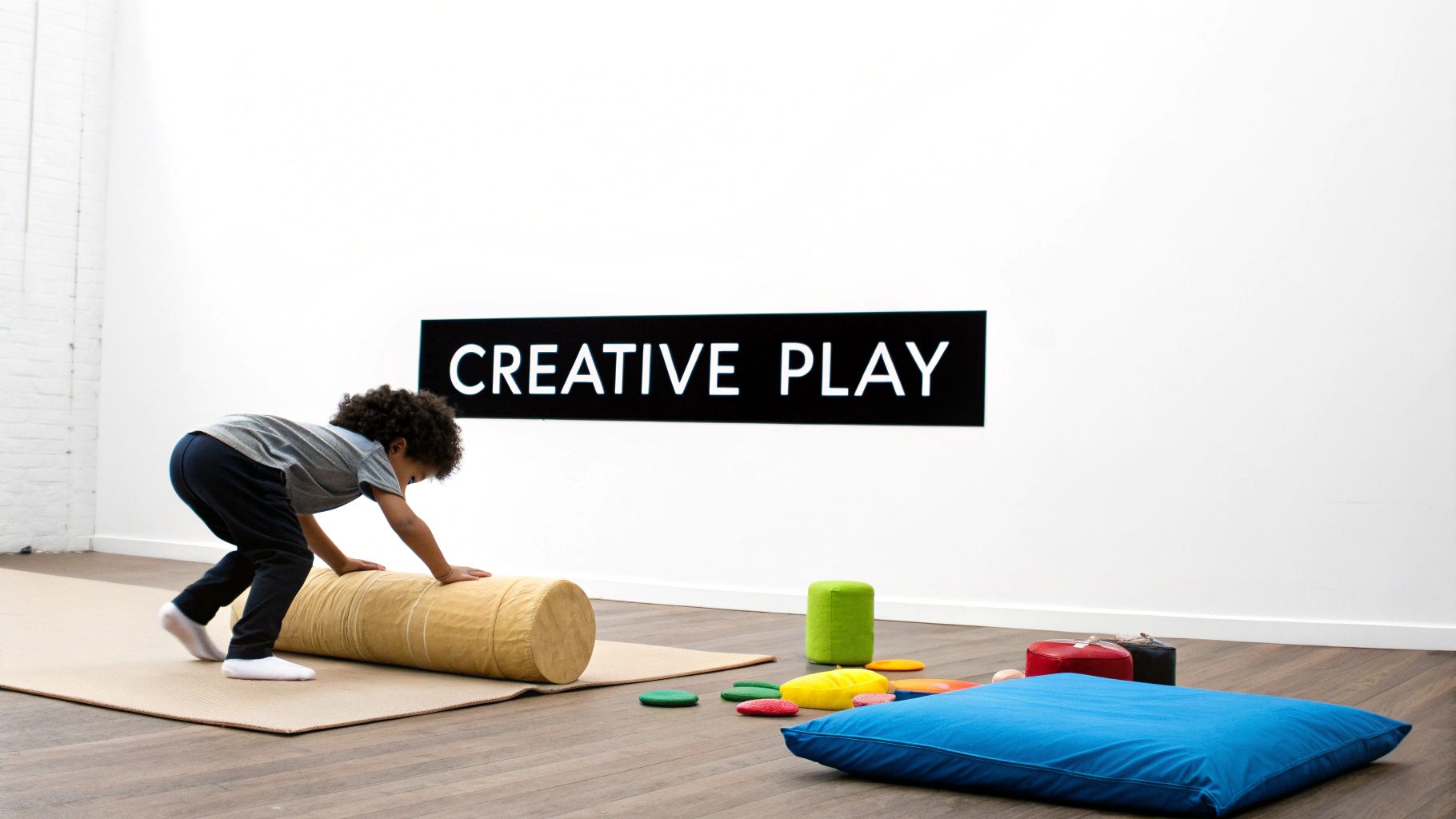 A child plays with soft objects on a mat in a room with a 'Creative Play' sign.