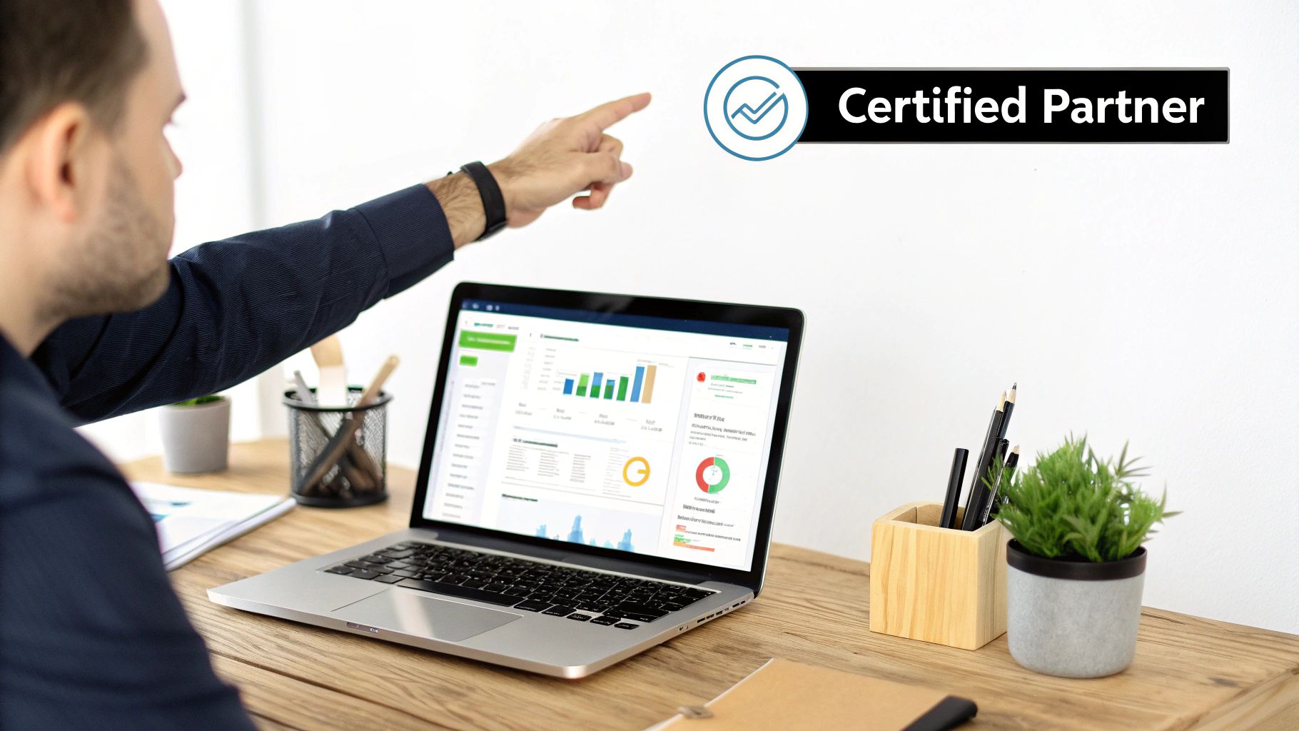 A man points at a "Certified Partner" logo while viewing data dashboards on his laptop at a wooden desk.