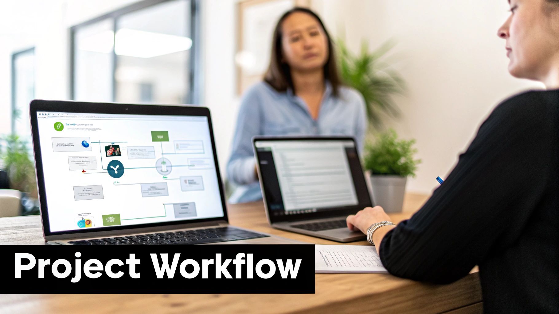 Two people are collaborating on project workflow diagrams and documents using laptops in an office.