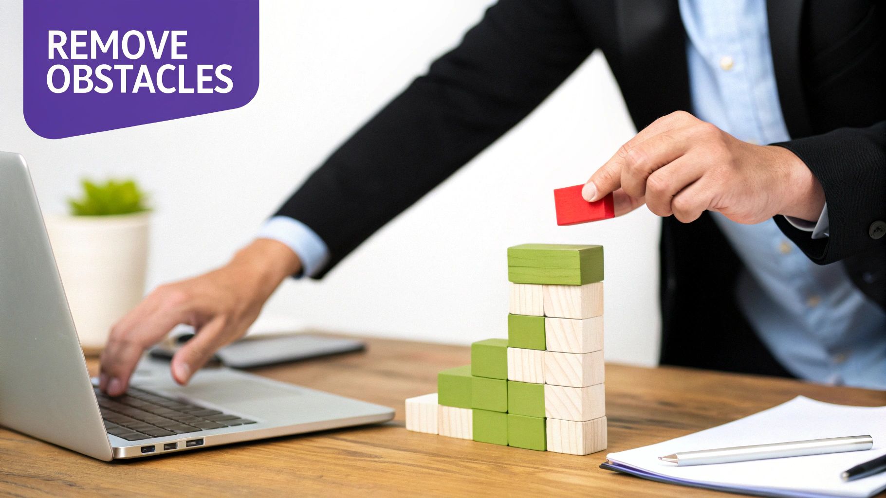 A person building a staircase with wooden blocks while working on a laptop, with text 'REMOVE OBSTACLES'.