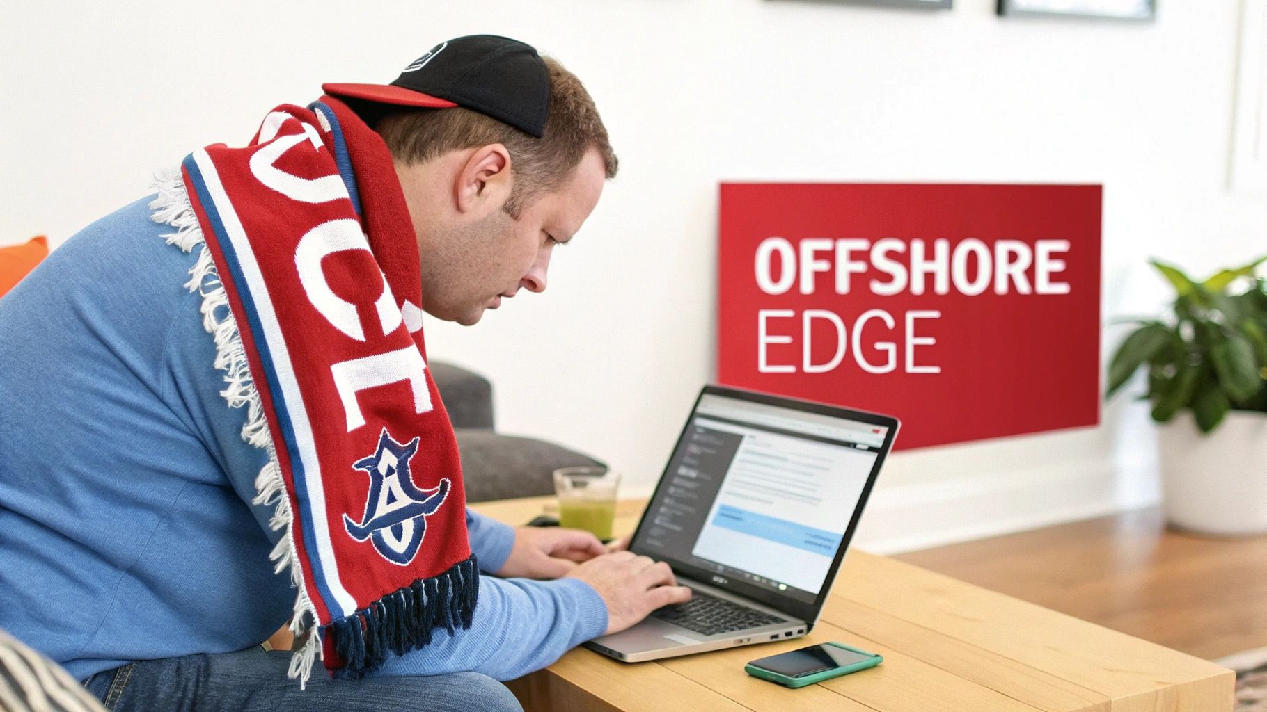 Sports Betting Indiana: Your Guide to sports betting indiana Offshore Sites 1 A man in a blue shirt and red sports scarf typing on a laptop at a wooden table.
