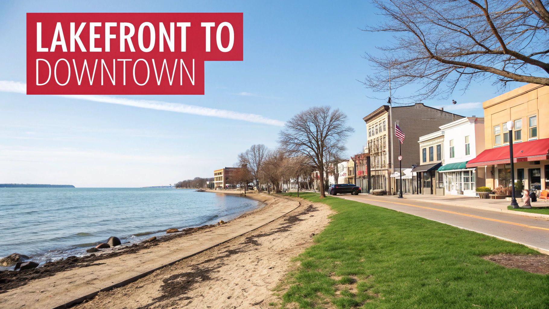A scenic view of a lakefront with a sandy beach adjacent to a charming downtown street lined with shops and buildings.