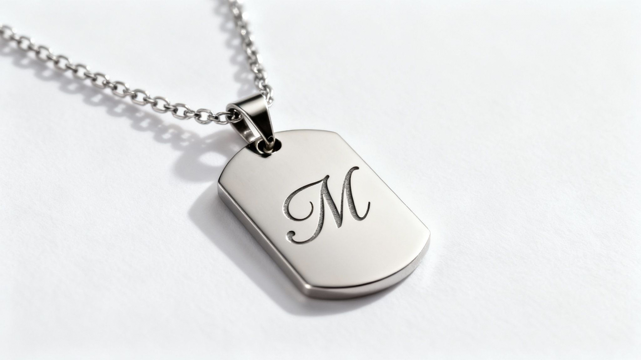 A close-up of a laser engraving a detailed design onto a stainless steel pendant.