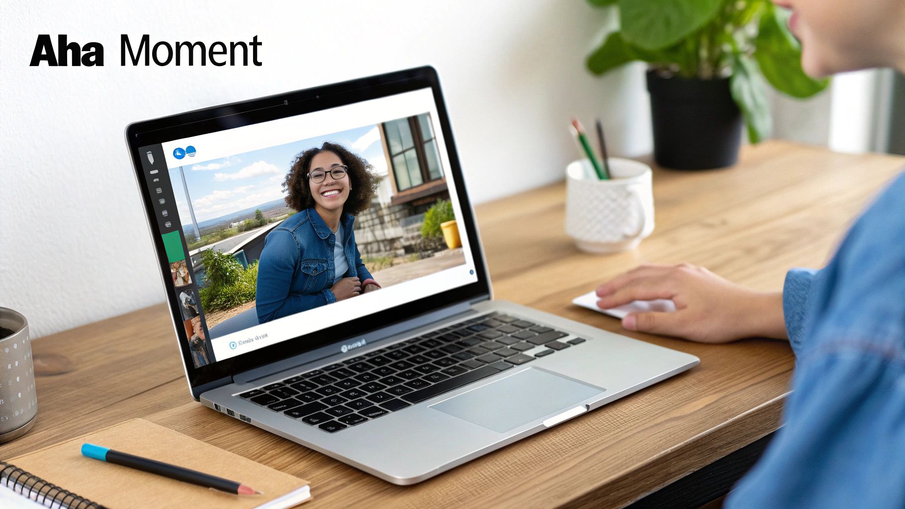 Person using a laptop for a video call with a smiling woman, on a wooden desk with office supplies.