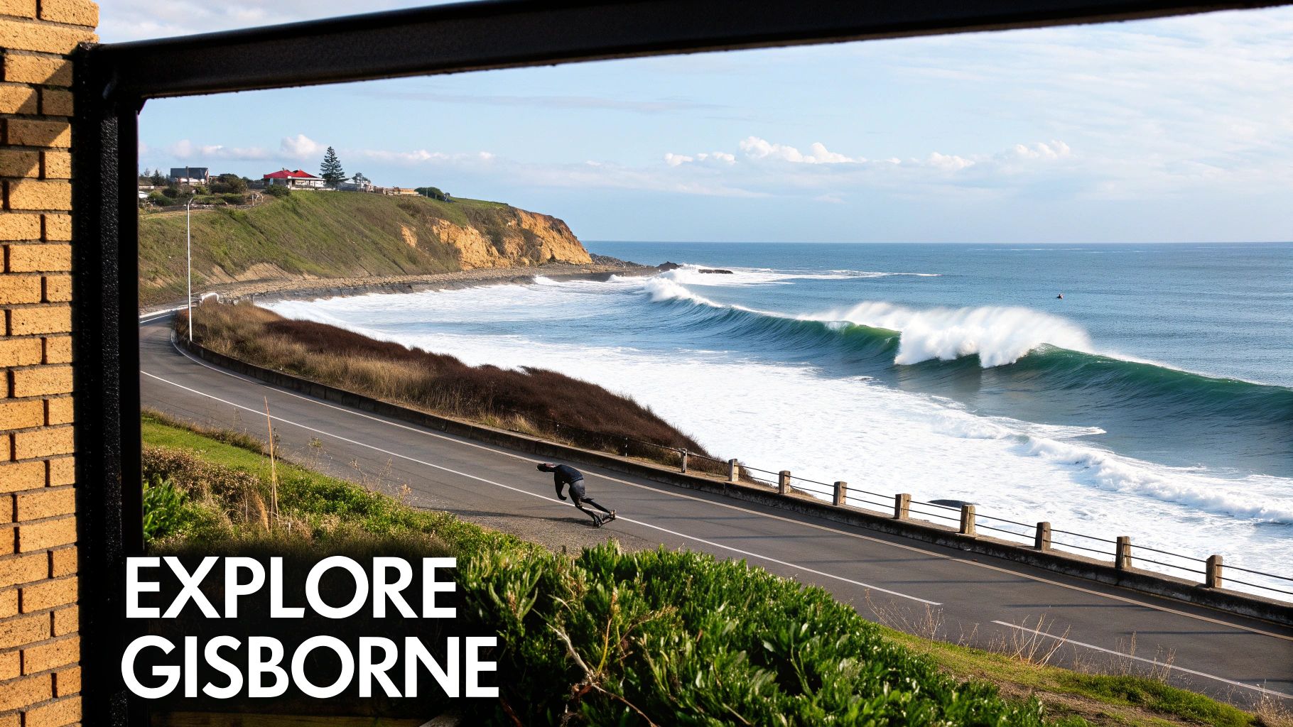 A longboarder carves on a coastal road next to powerful green ocean waves and cliffs.