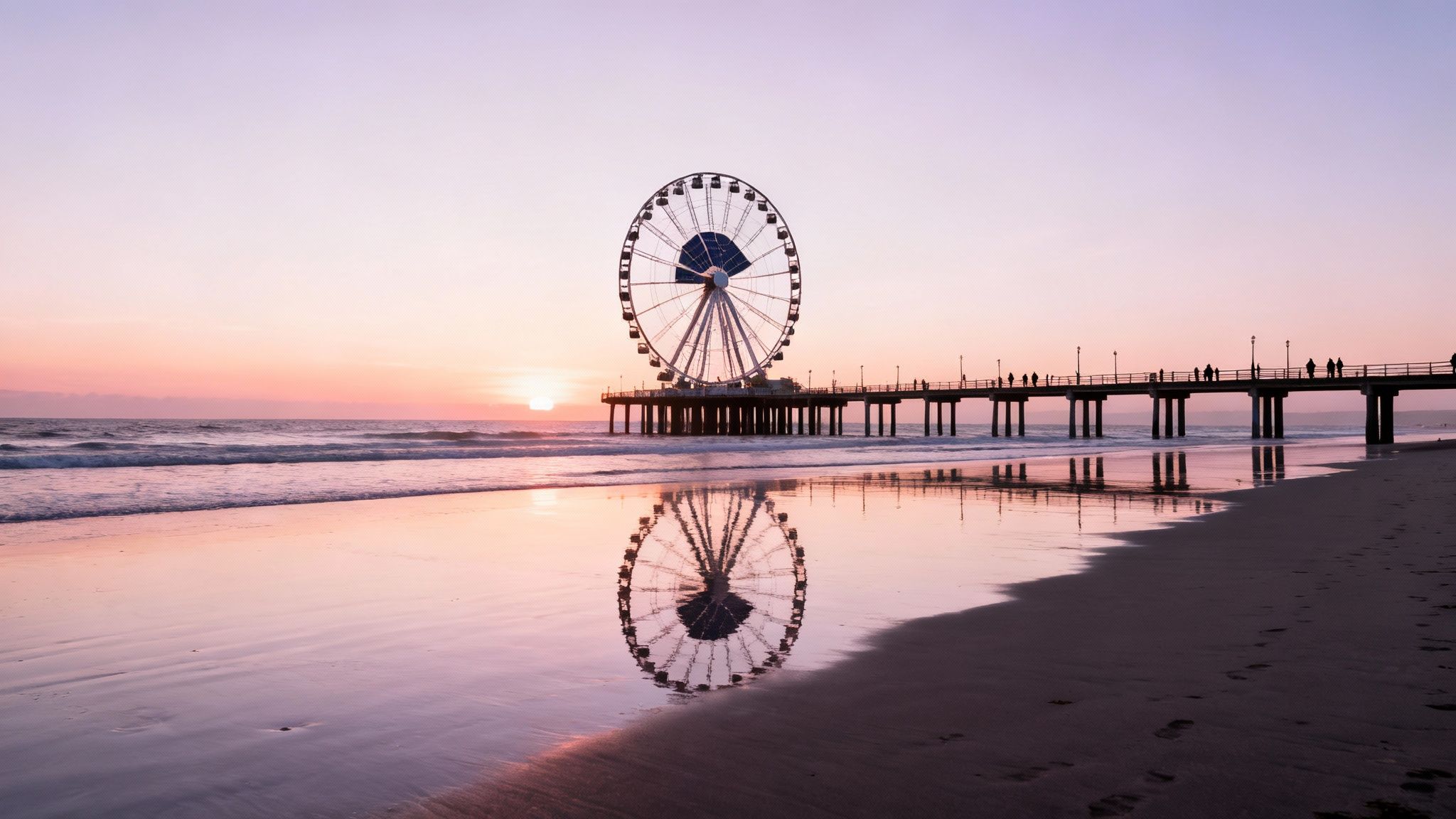 Stunning sunset over a pier with a ferris wheel, reflecting on a wet beach.