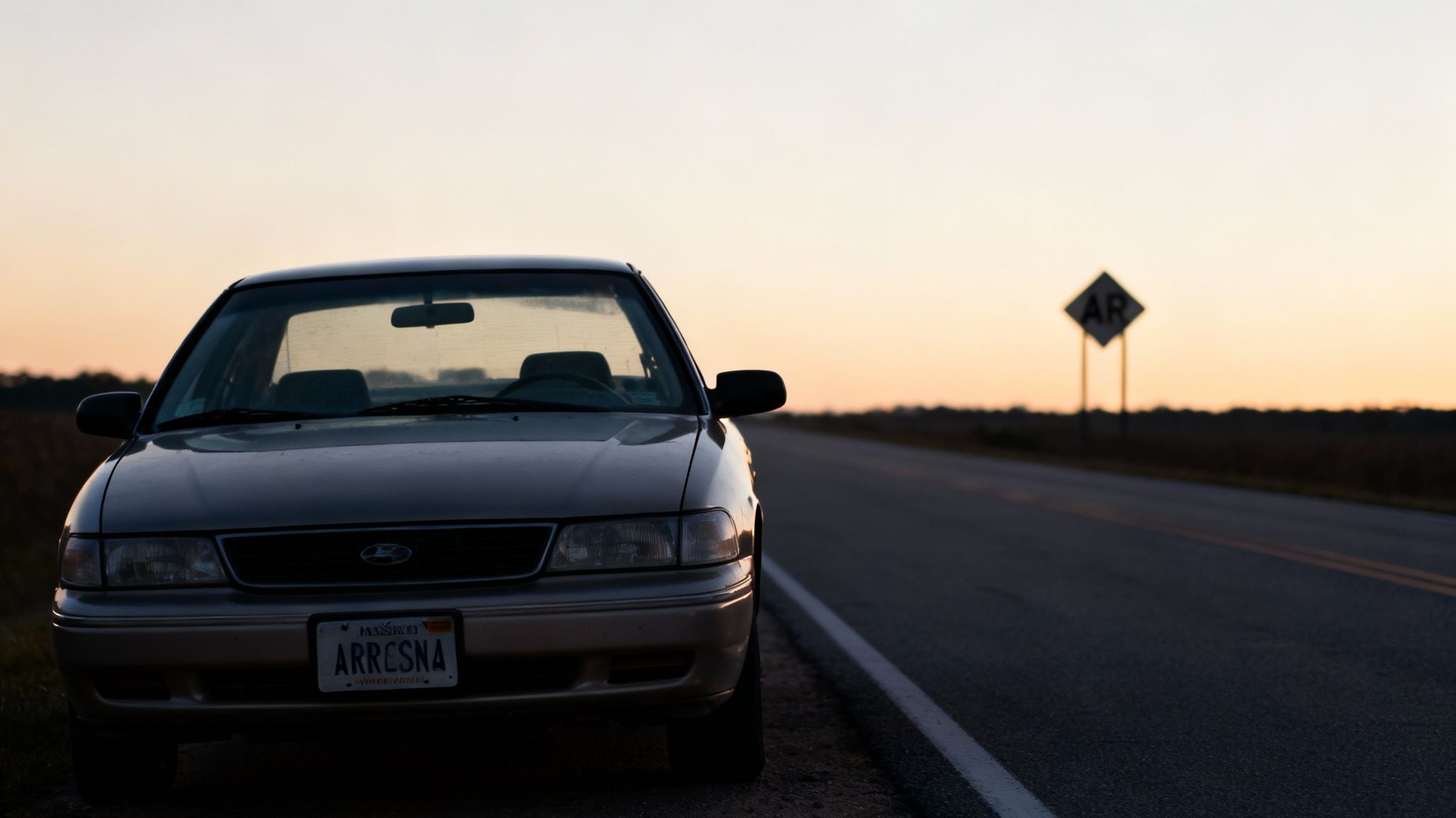 AR DWI Laws: A Simple Guide to What Happens Next 1 A vintage sedan with an 'ARRESNA' license plate parked by a road at sunset.