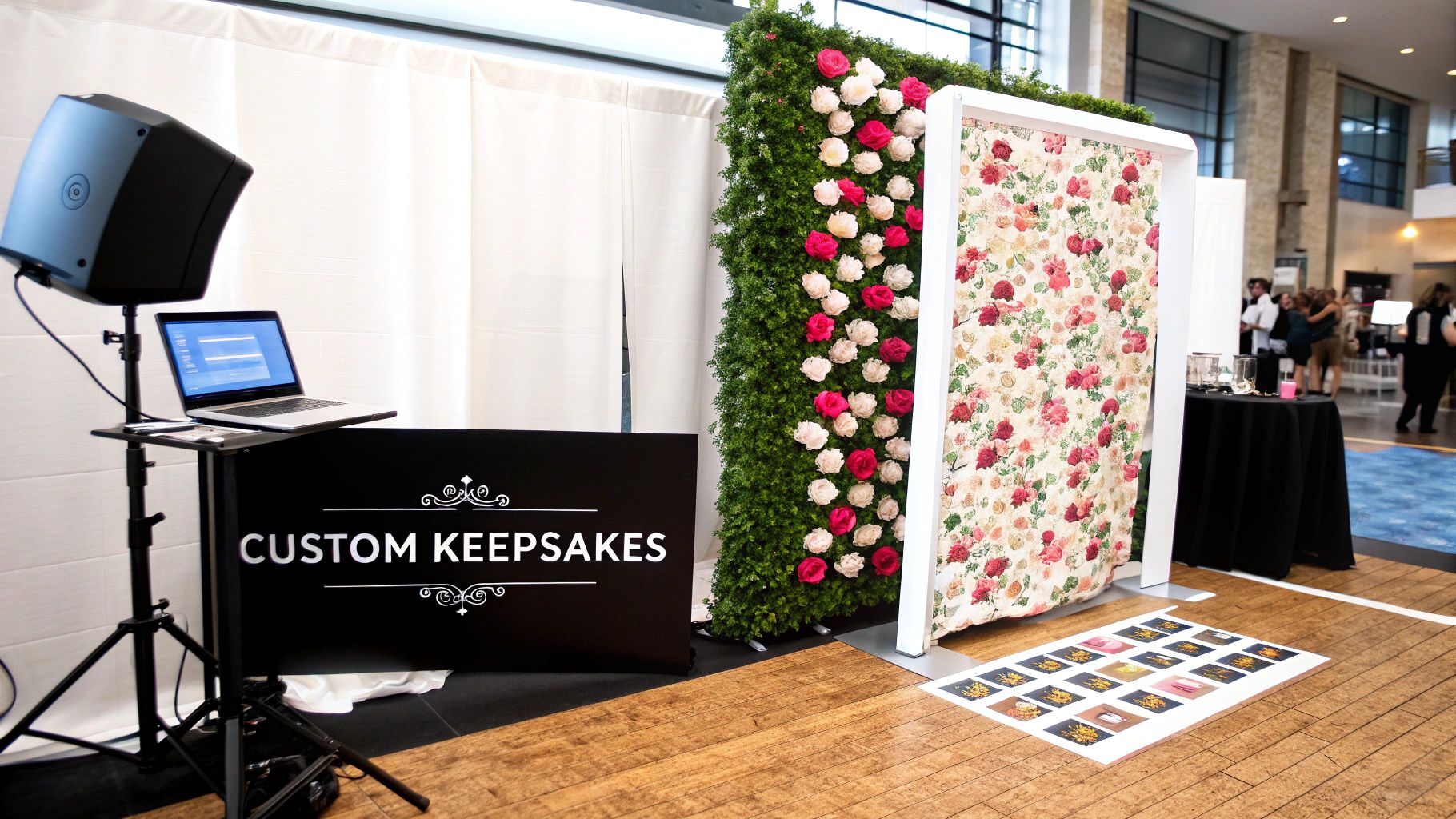 A custom keepsakes photo booth with a flower wall, laptop, and floral backdrop.