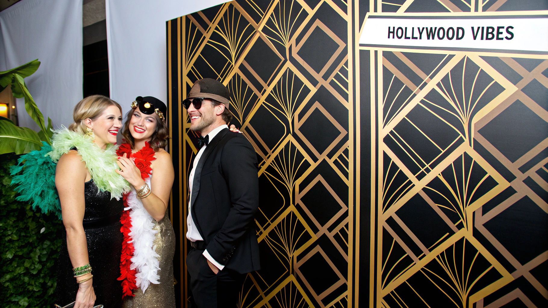 A vibrant, themed photo booth backdrop featuring a tropical jungle scene with lush greenery and colourful flowers.