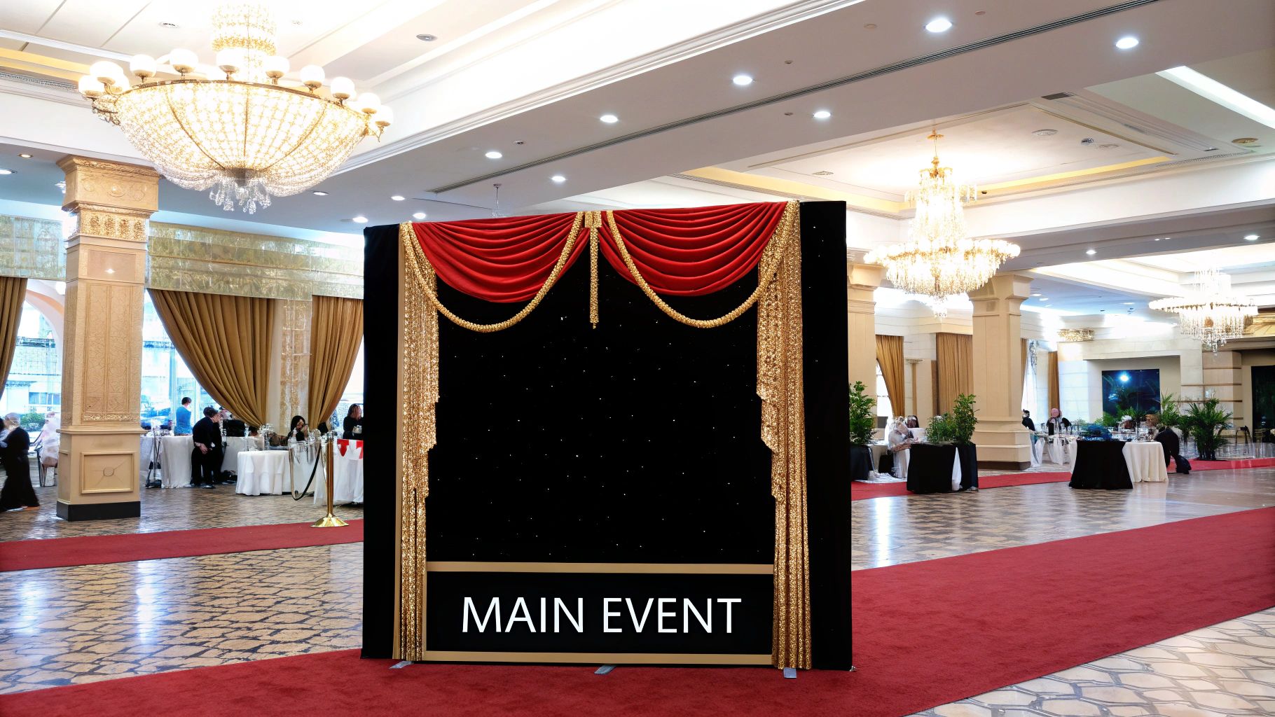 A stylish photo booth setup with a shimmering gold backdrop, balloons, and elegant lighting at an event.