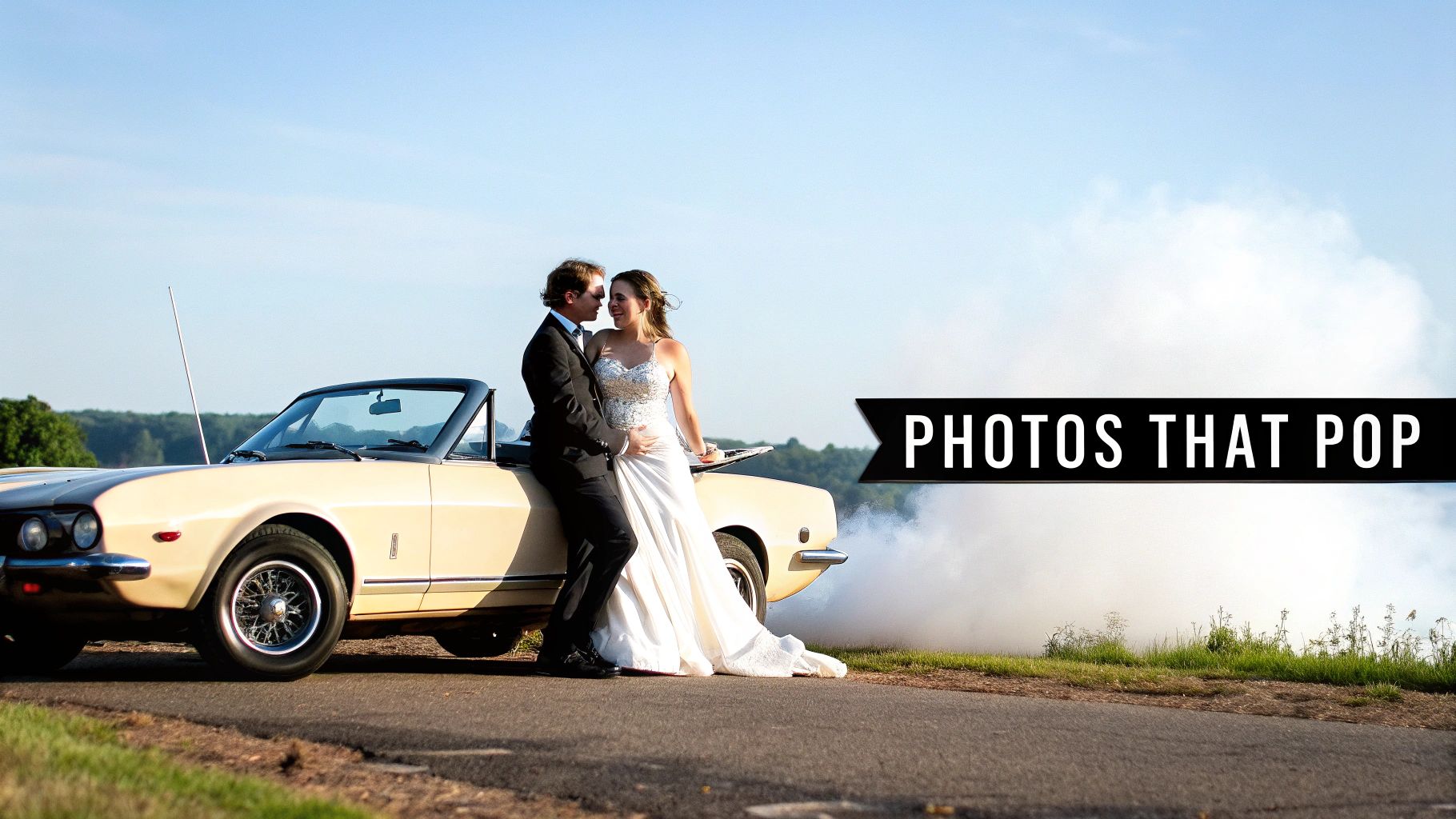 A newlywed couple embracing by a classic convertible car on a scenic road with smoke.