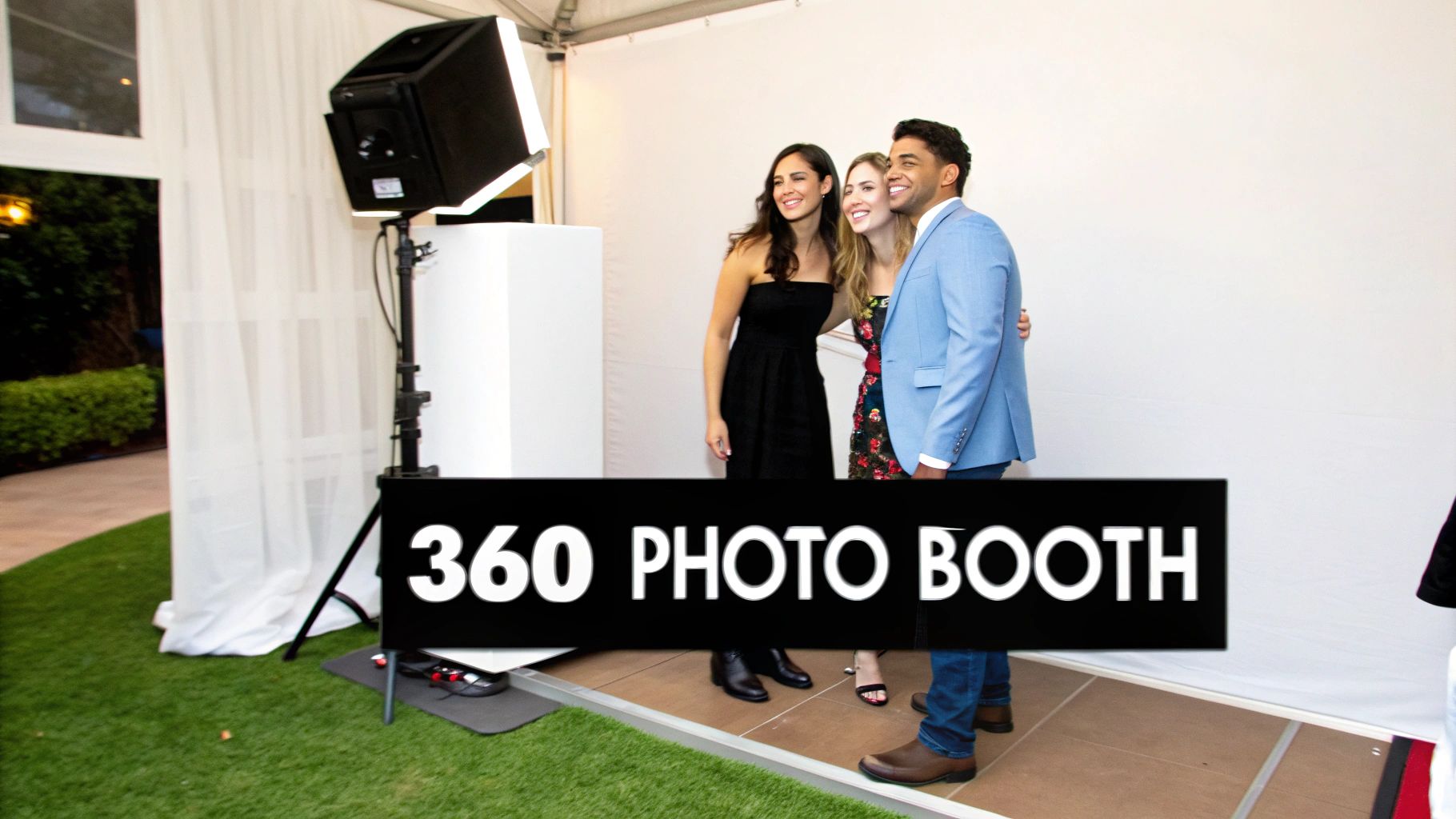 Three people posing and smiling at a 360 photo booth at an outdoor event