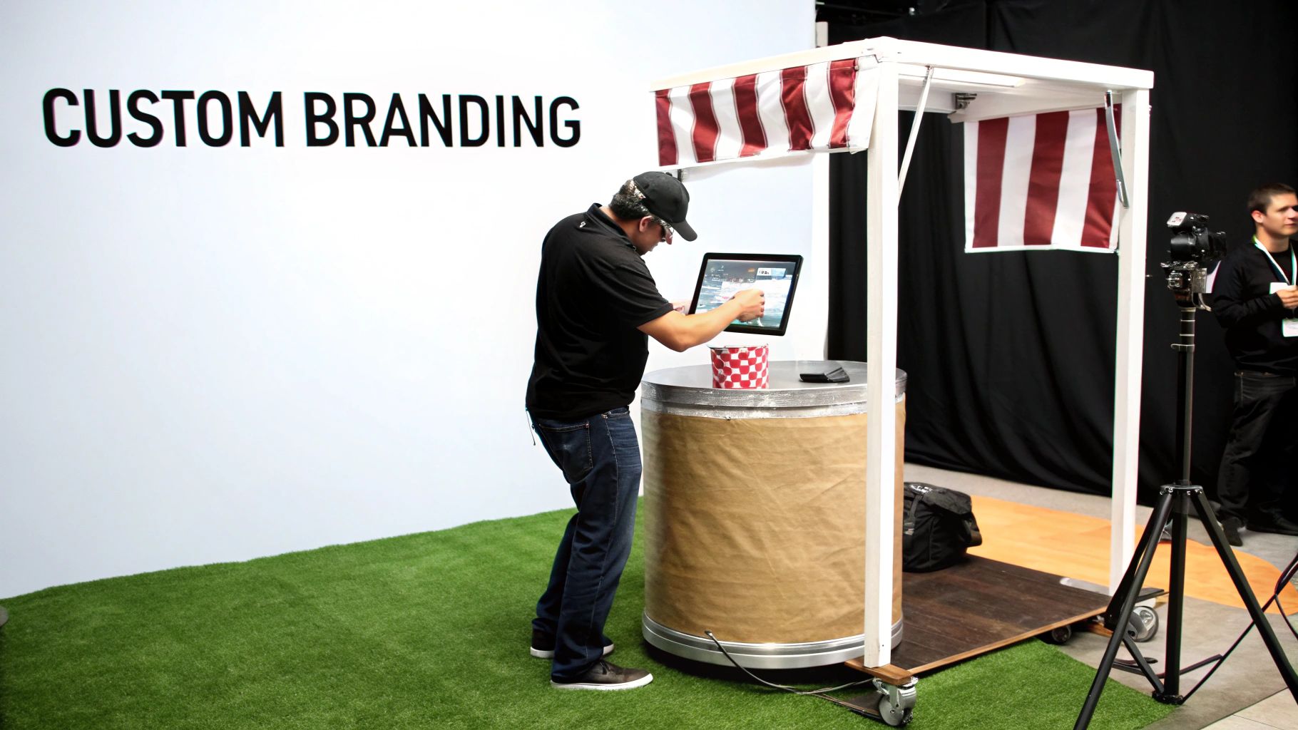 A man in a black shirt uses a tablet at a custom branding event booth setup.