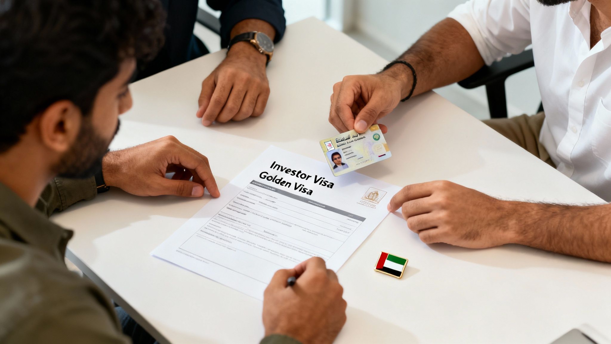 Three men discussing an 'Investor Visa Golden Visa' document with a UAE ID card on a white table.
