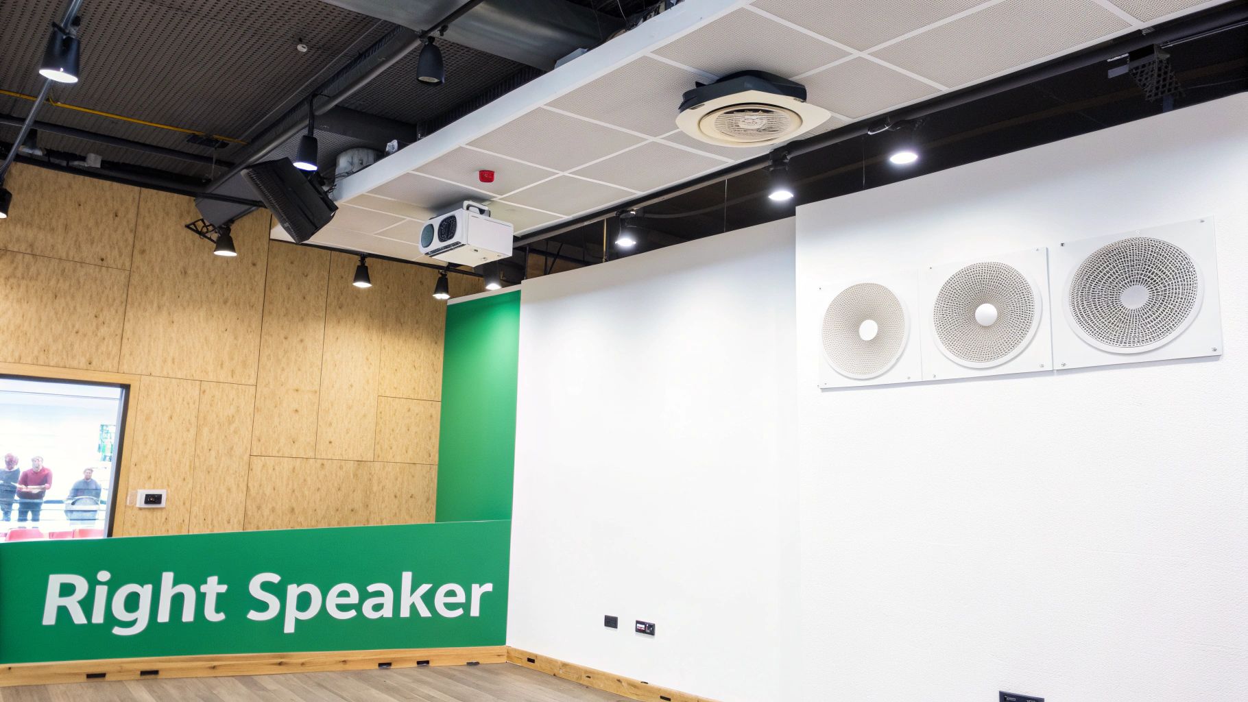 Modern meeting room featuring a public address speaker system, ceiling projector, and track lighting.