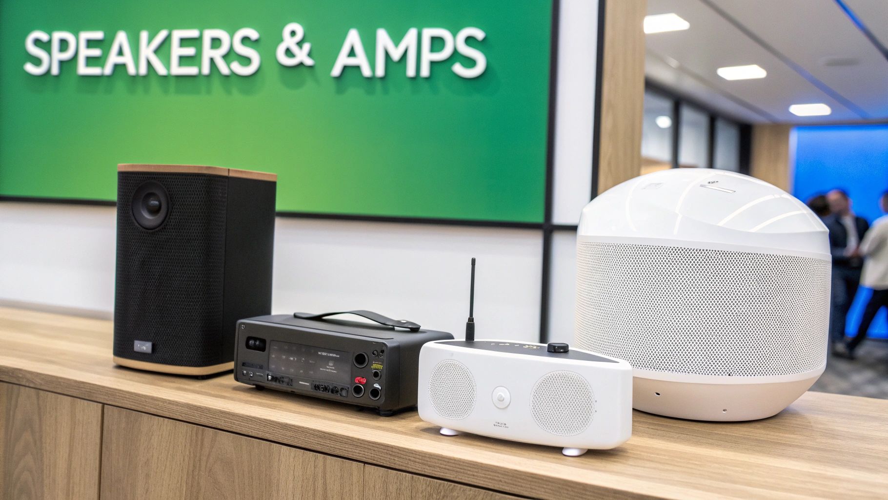 A display of various audio devices, including different speakers and an amp, on a wooden counter.