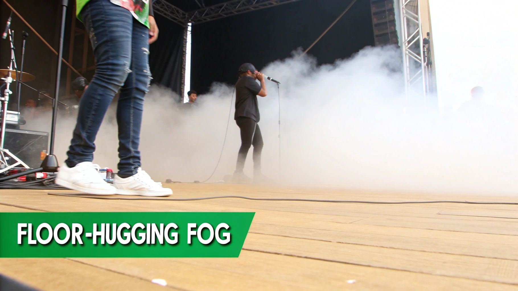 Performers on a stage enveloped by floor-hugging fog during a live event.