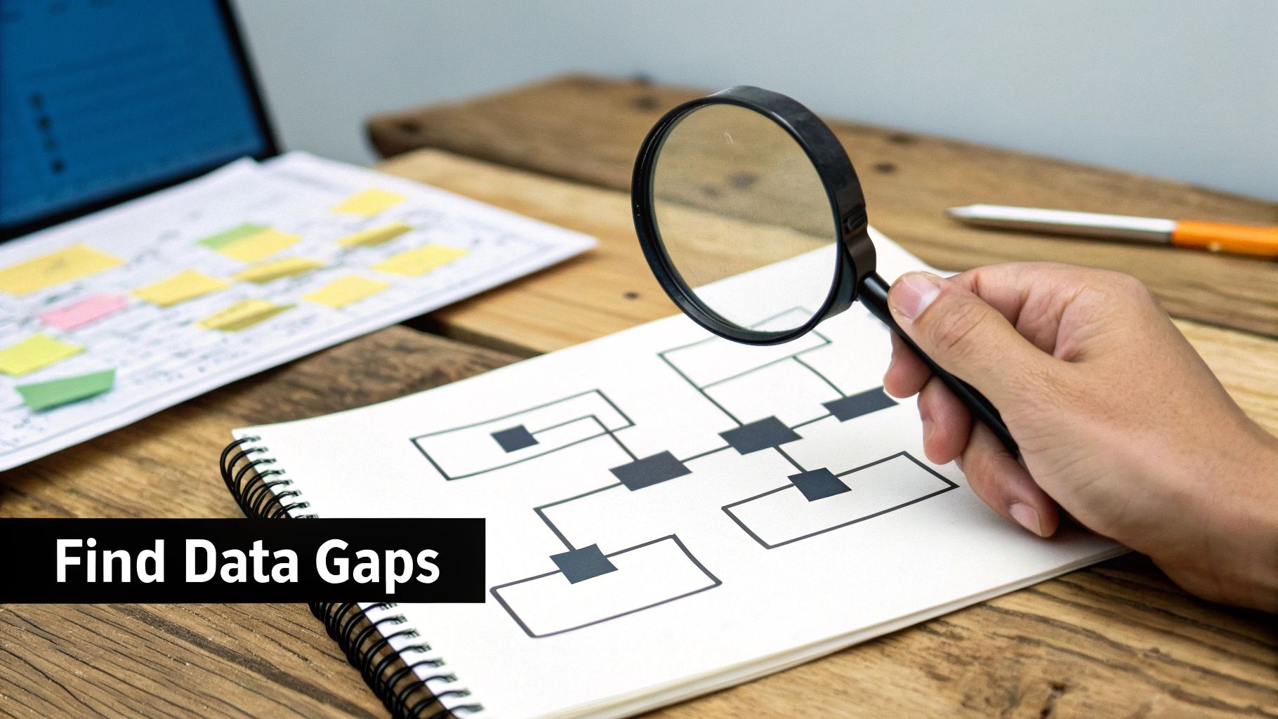 A hand holds a magnifying glass over a diagram to find data gaps on a wooden desk.