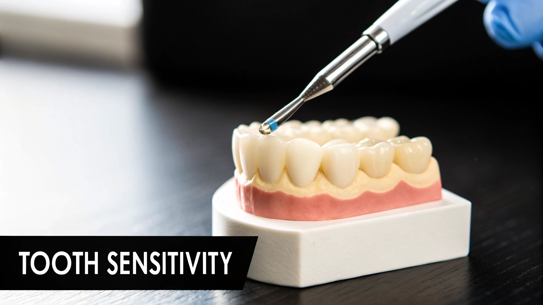 A dental model shows a tool applying desensitizing gel to a tooth, illustrating treatment for sensitivity.