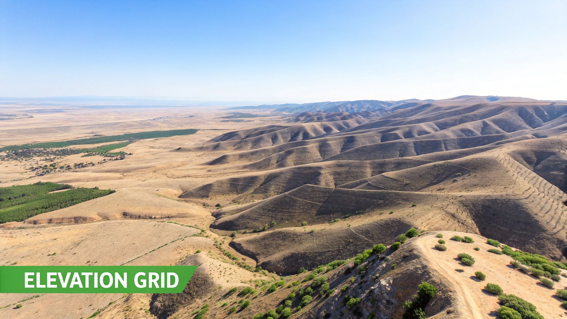 An aerial view of arid, rolling hills and a vast, flat plain with some green vegetation patches.