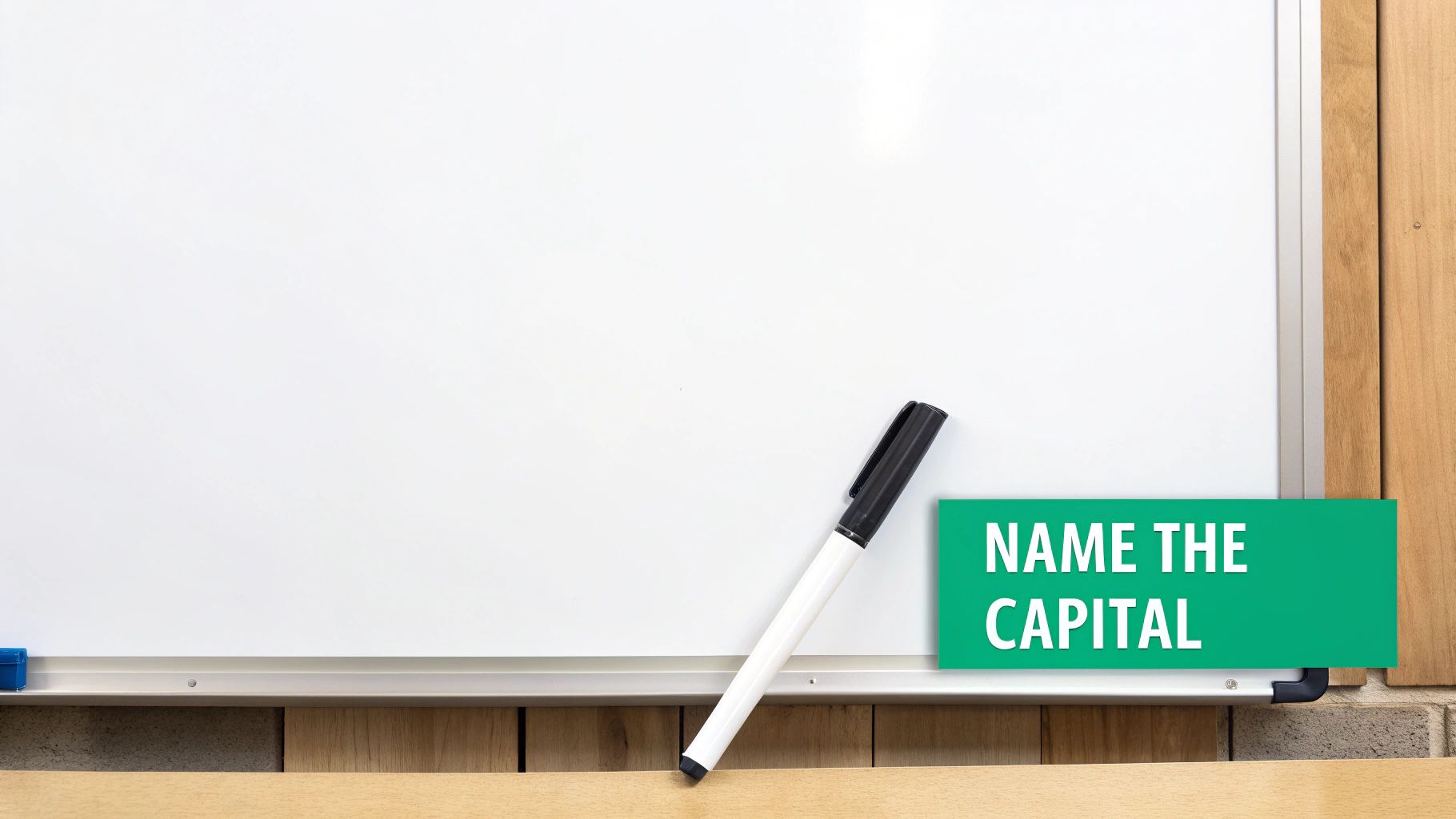 A whiteboard with a black and white marker and a green sign asking to name the capital.