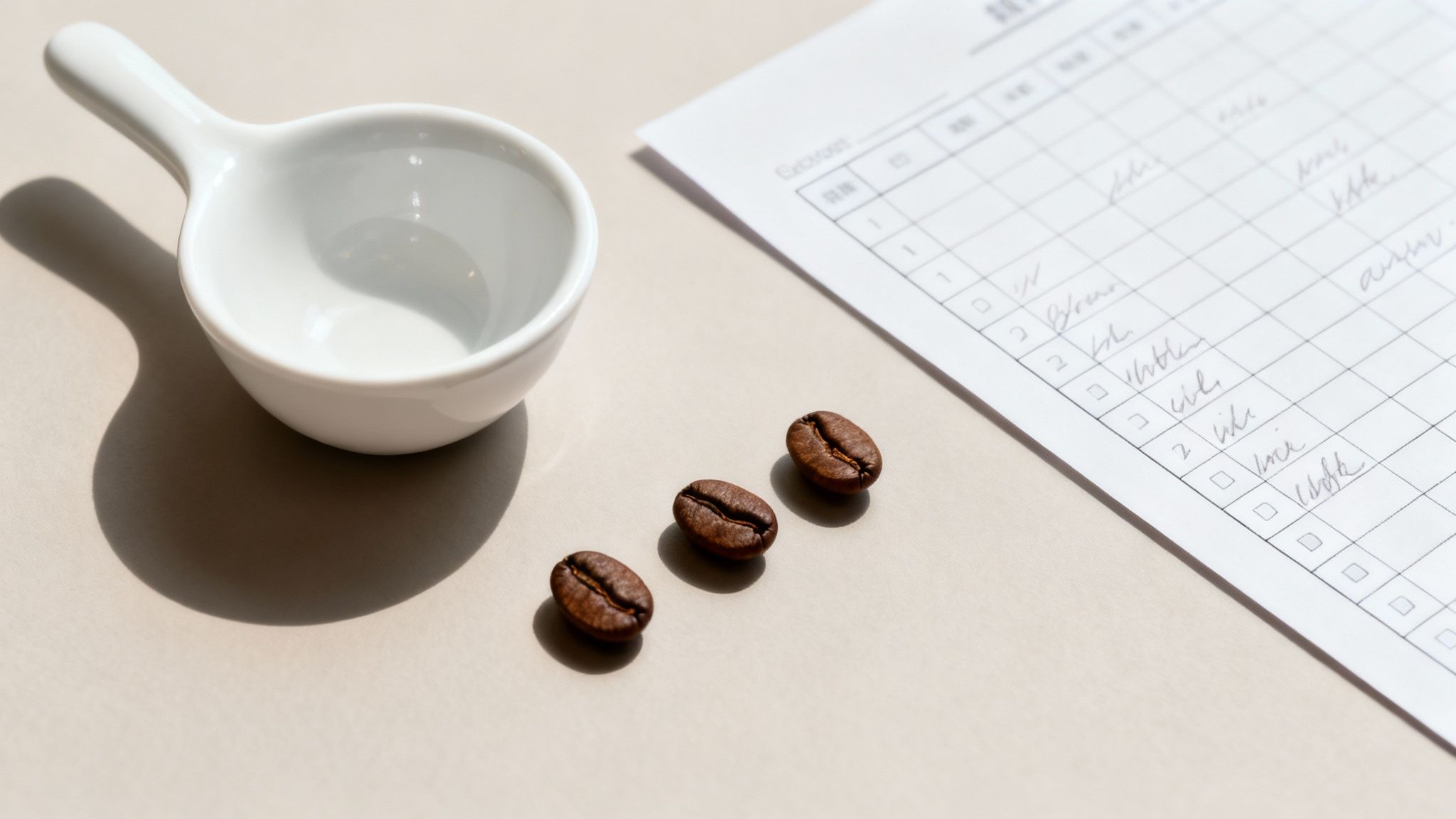 A close-up of a hand inspecting green, unroasted coffee beans