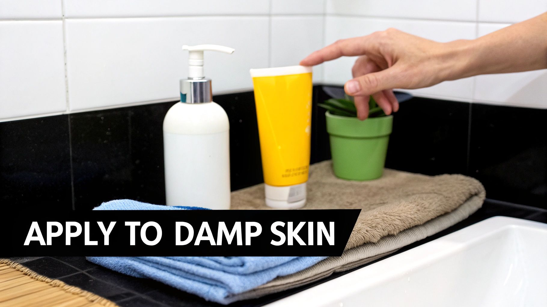 Hand reaching for skincare products on bathroom counter with towels, demonstrating moisturizer application routine