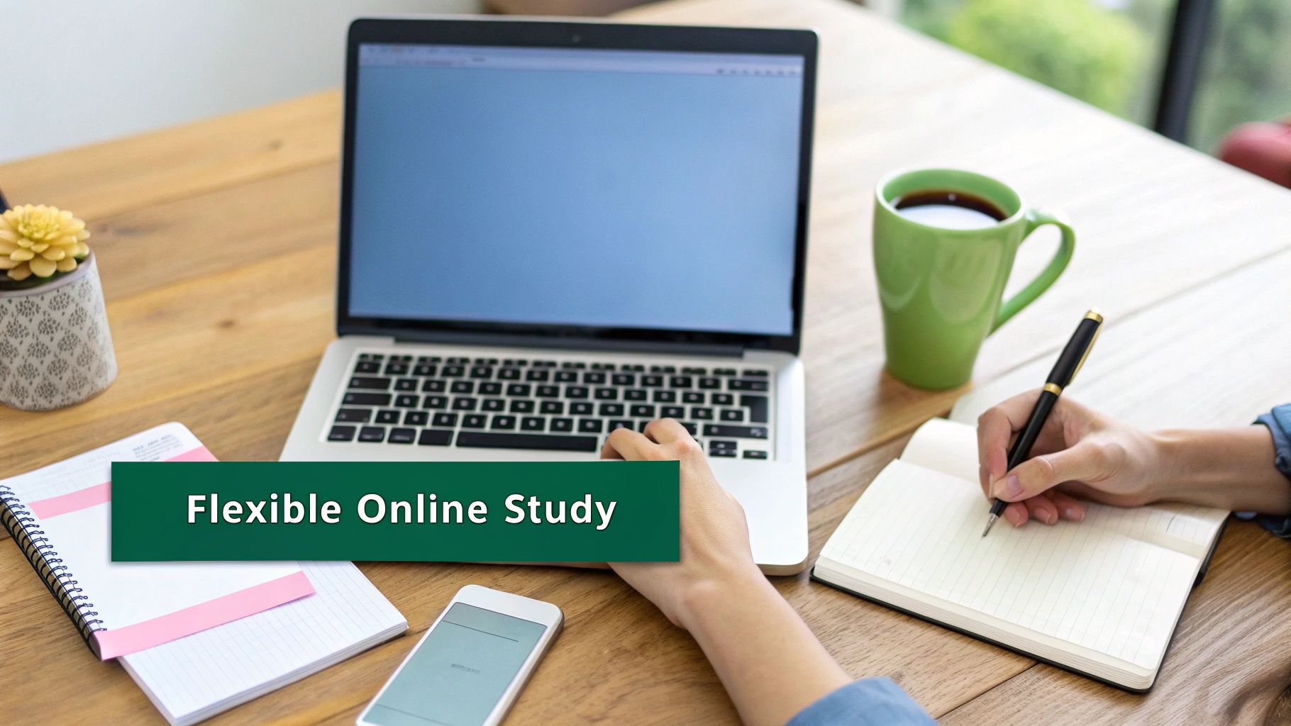 Person studying online at a wooden desk with a laptop, notebook, and coffee mug, promoting flexible online study.