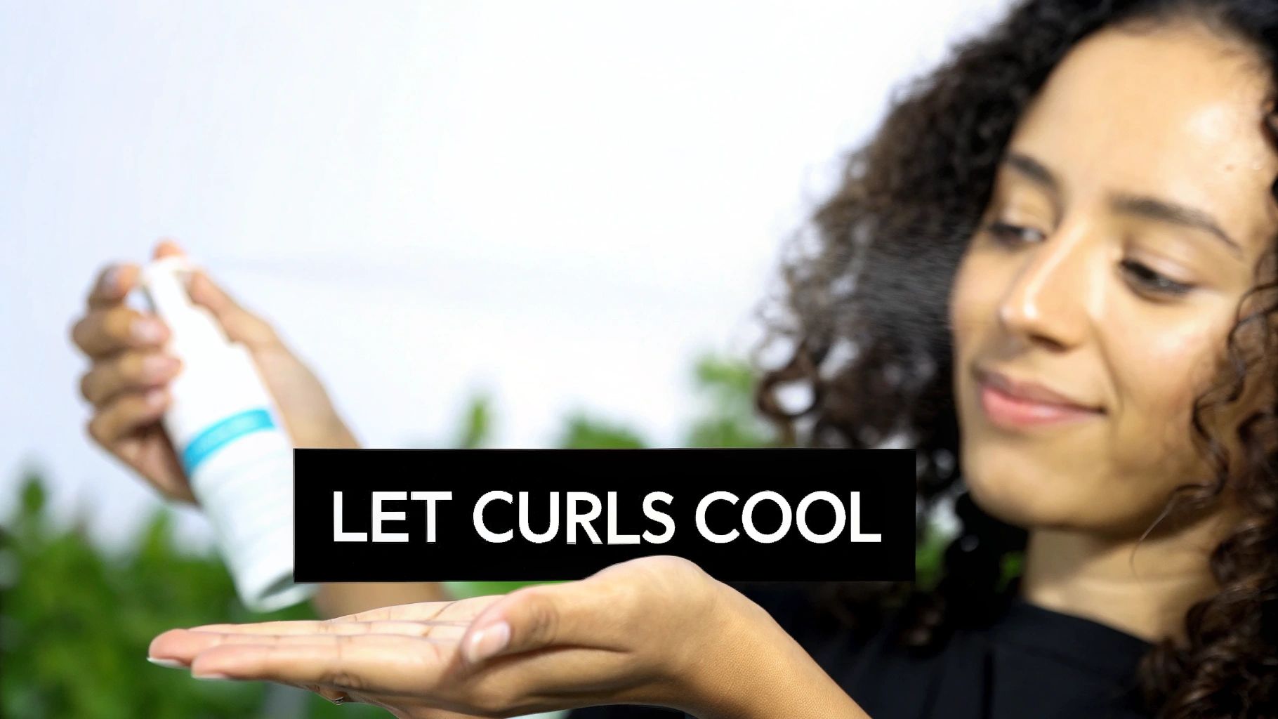 A woman with perfectly styled, curled hair smiling and touching her hair.
