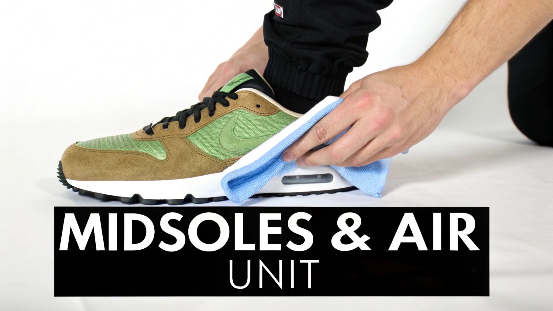A person cleaning the white midsole and visible air unit of a brown and green Nike sneaker with a blue towel.