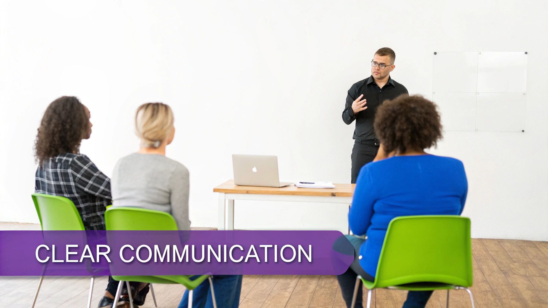 A man presents to three women seated in green chairs during a clear communication training.