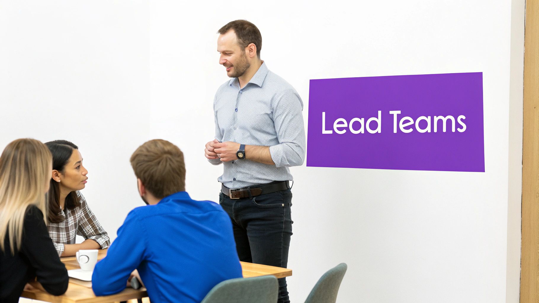 A man leads a team discussion, standing while others sit at a table. A purple sign reads 'Lead Teams'.
