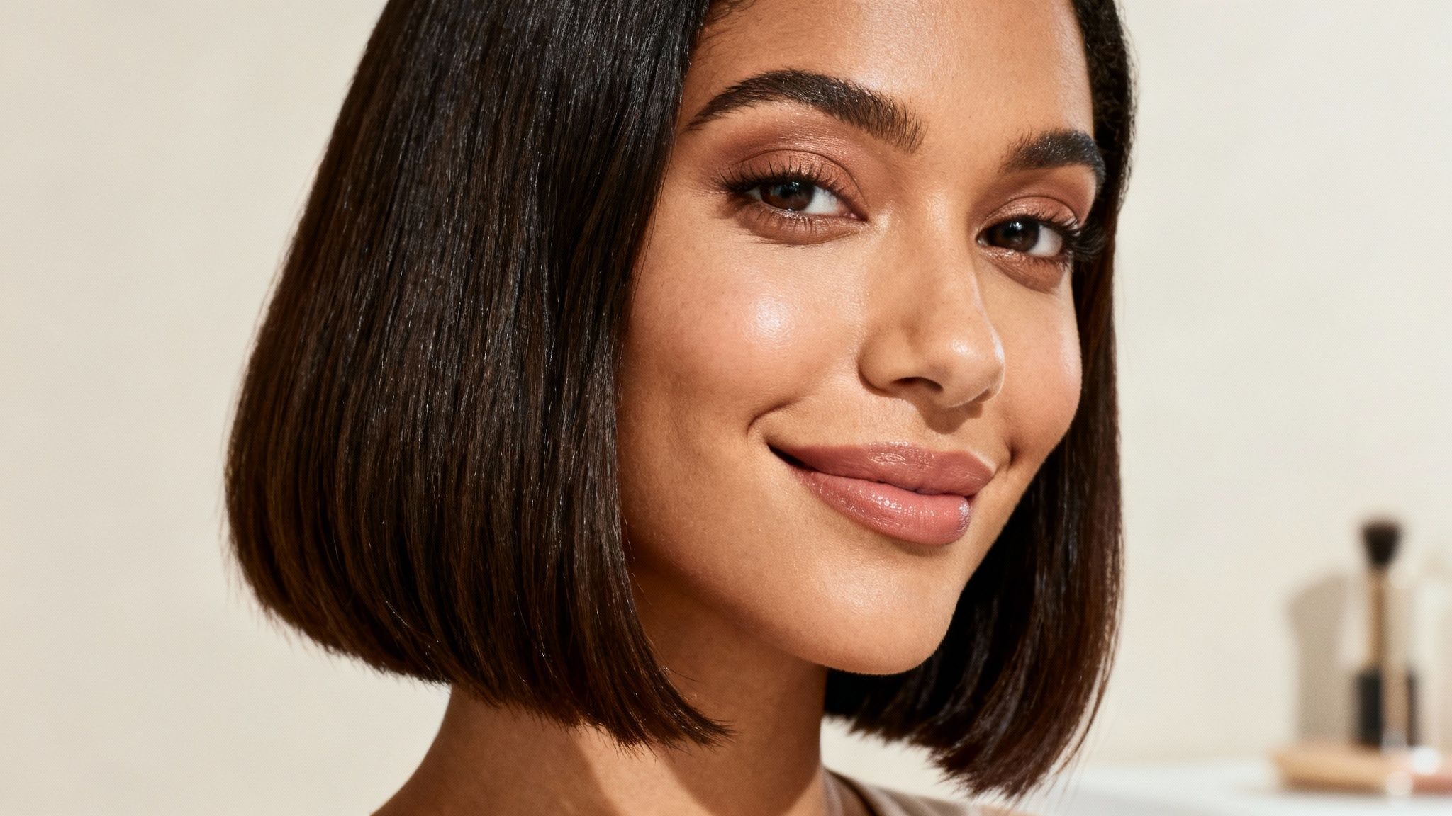 Close-up of a smiling woman with a dark bob haircut and natural makeup.