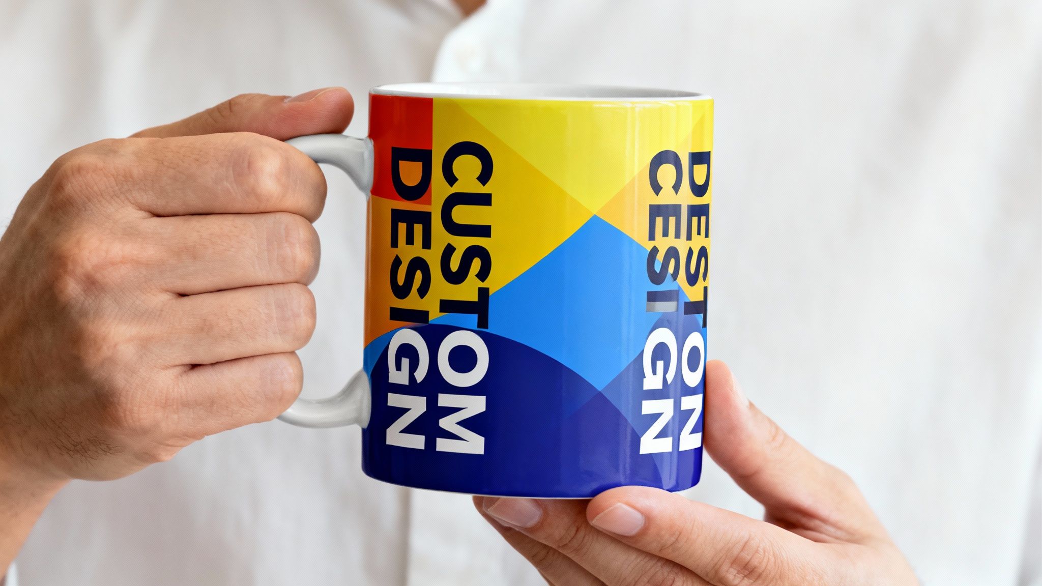 A person holds a white ceramic mug with a vibrant red, yellow, and blue custom design.