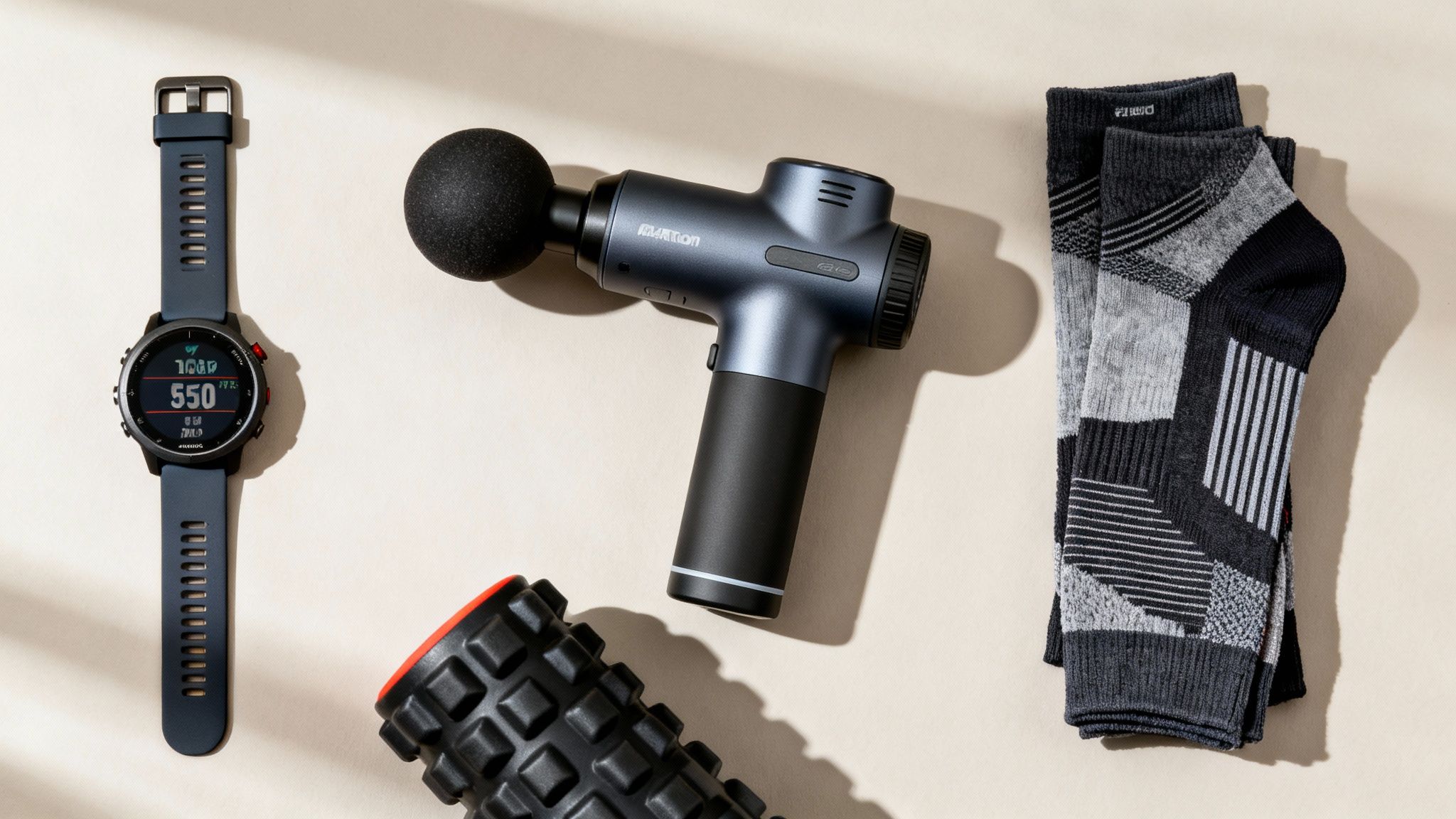 Running essentials for athletes: smartwatch, massage gun, foam roller, and athletic socks.