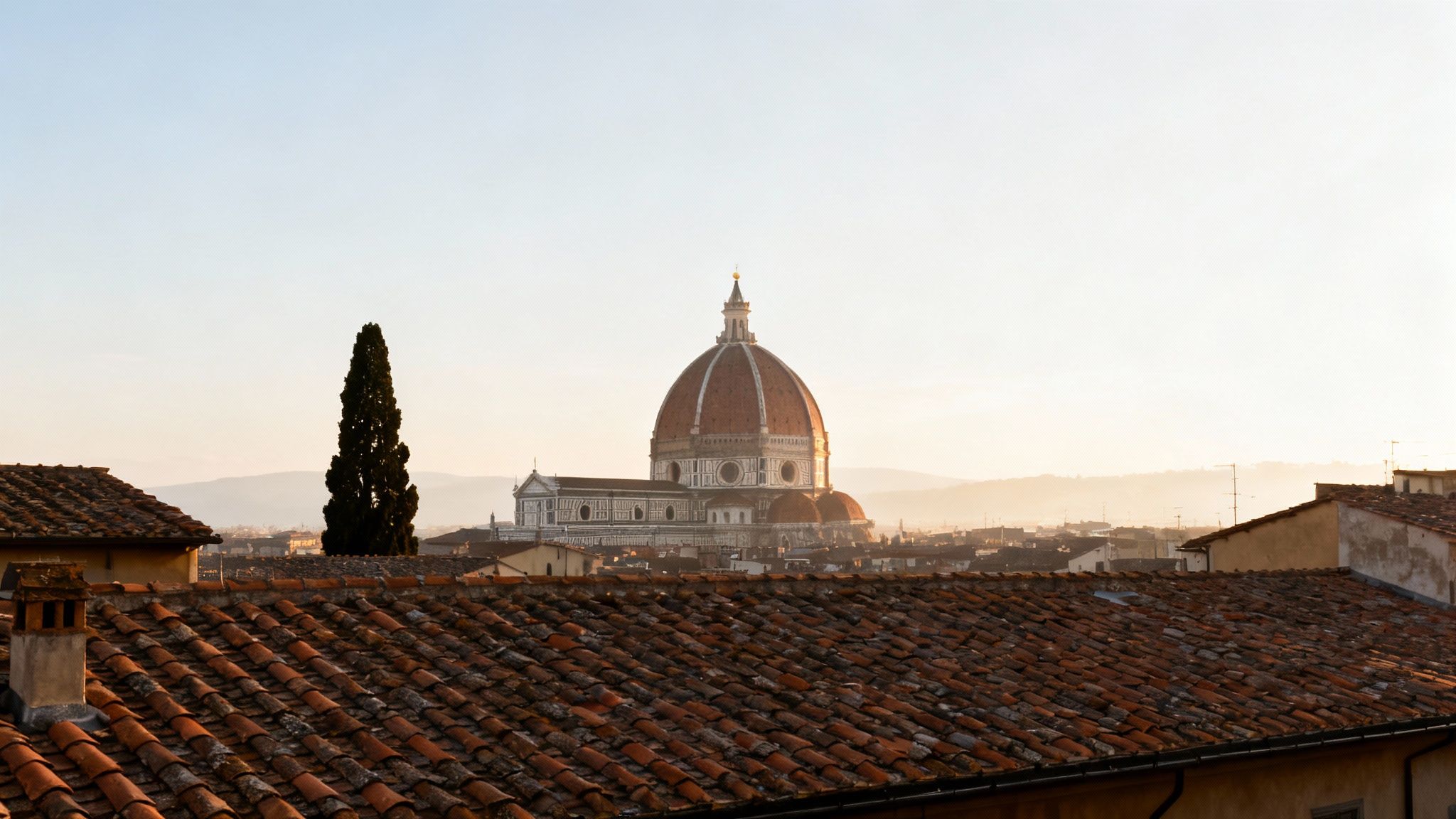 Panoramic view of Florence's iconic Duomo cathedral rising above historic terracotta rooftops at sunset.