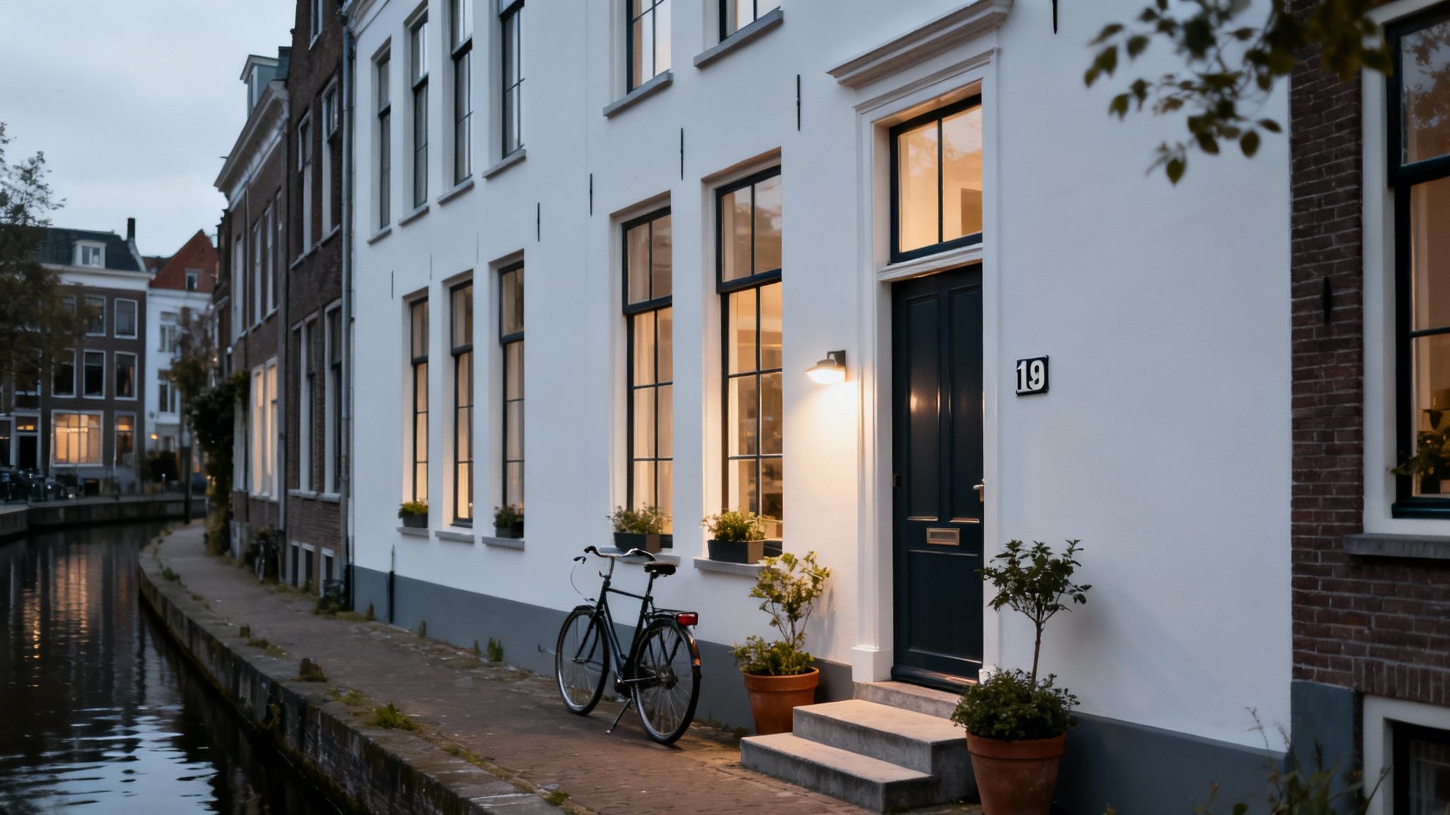 A picturesque evening scene of traditional Dutch canal houses, with a bicycle parked near a bright white home.